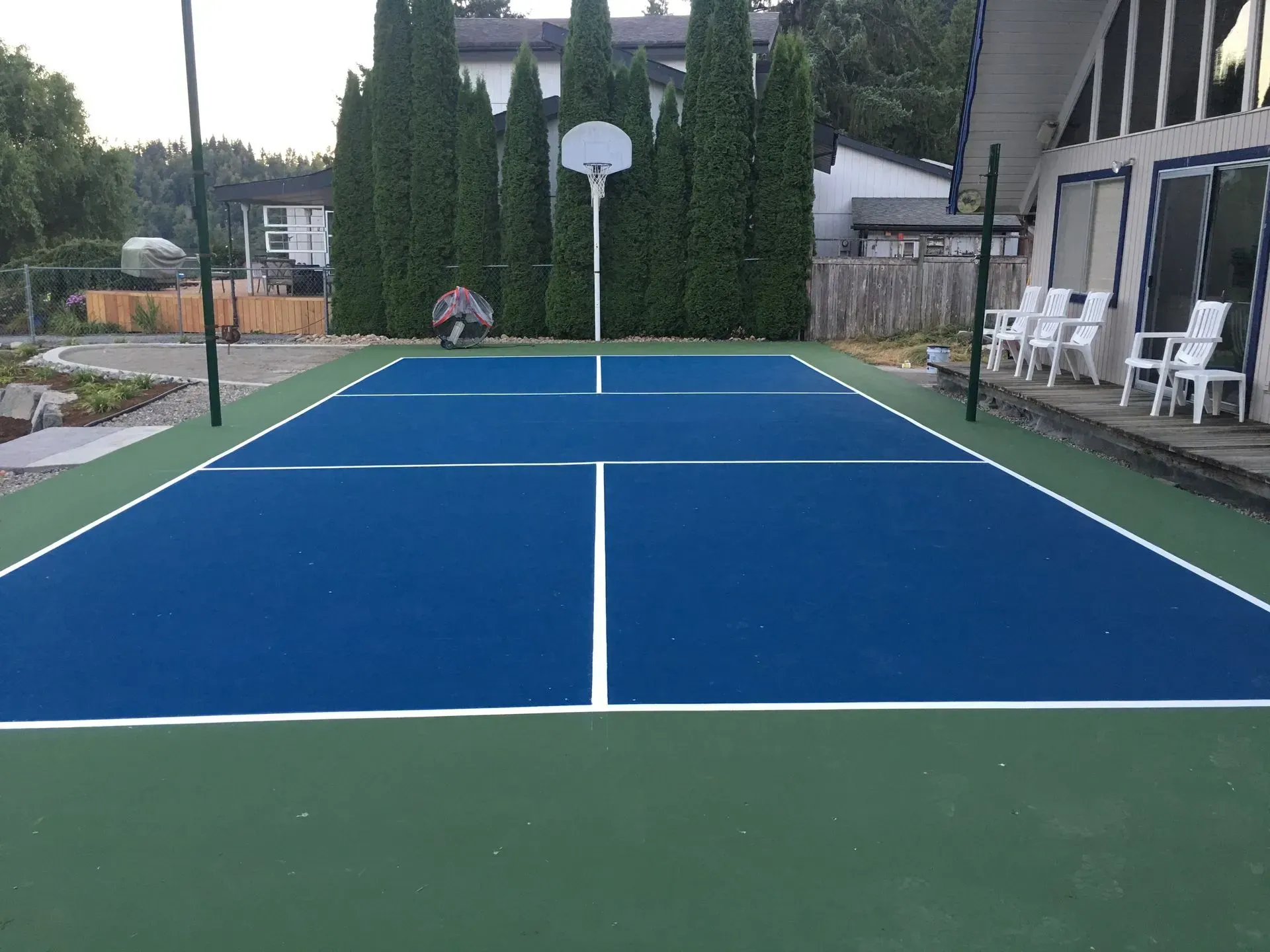 Blue and green pickleball court with white lines, person near the net.