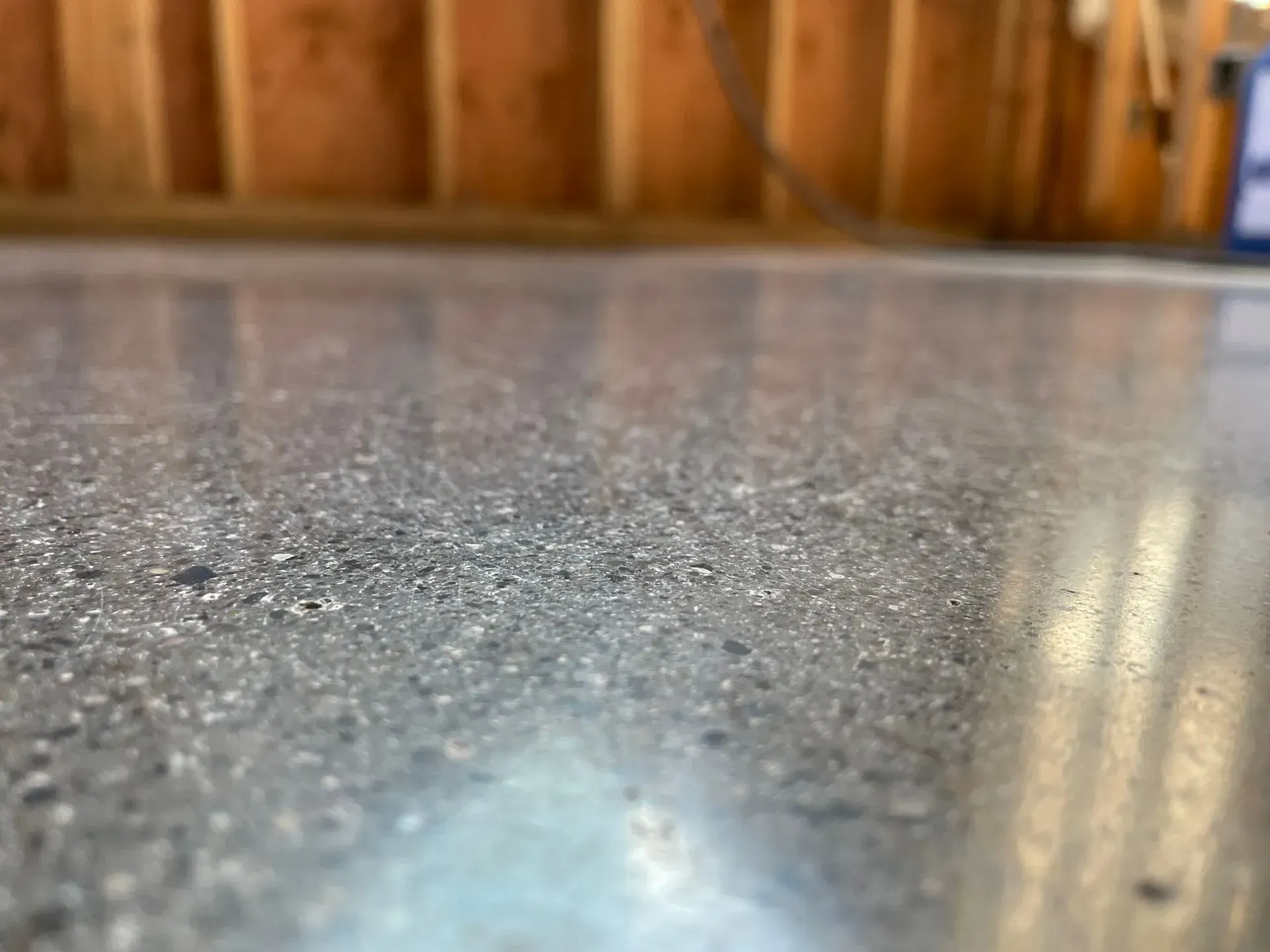 Close-up of a polished concrete floor with wood-framed wall in the background.