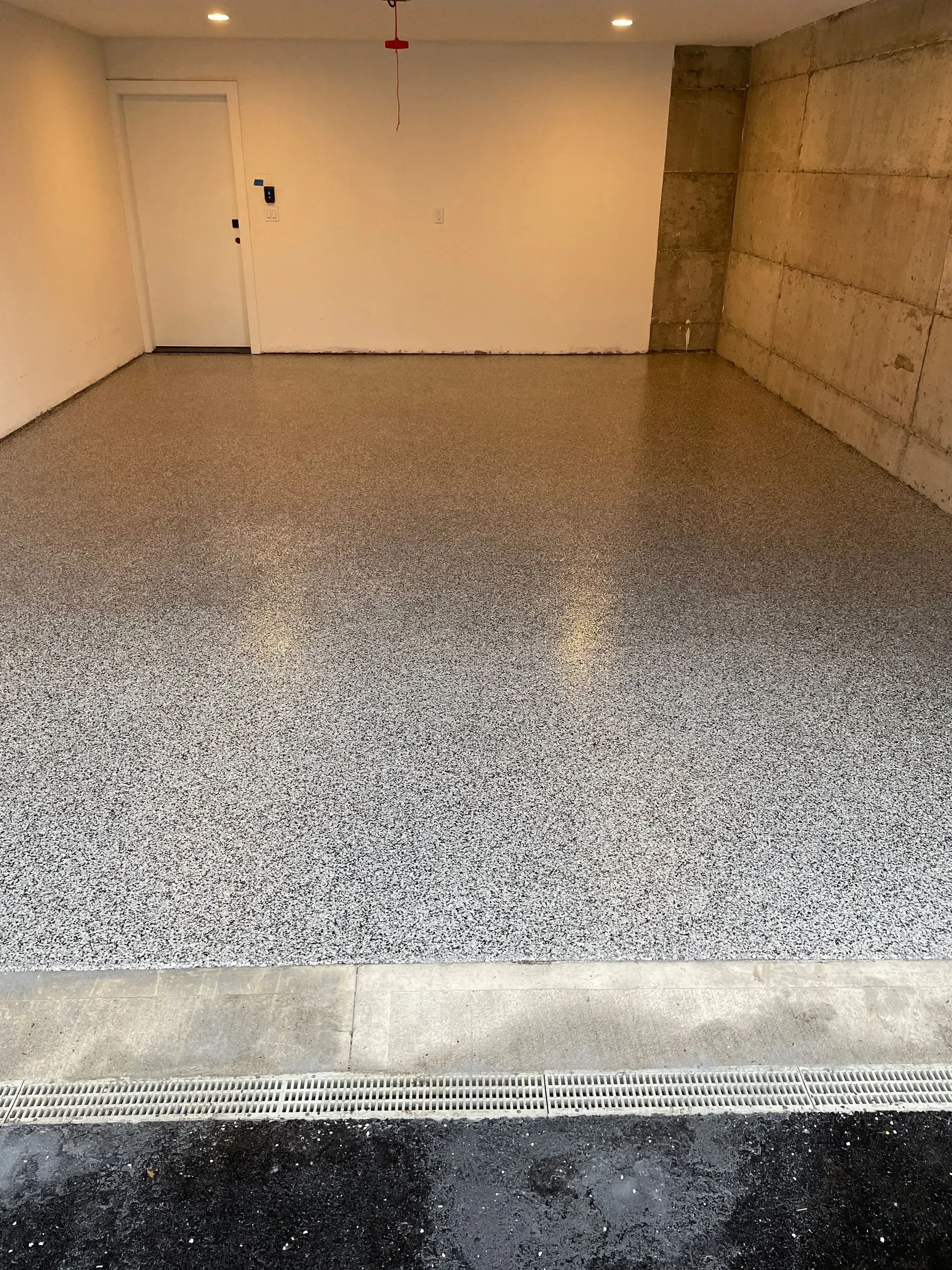 Garage interior with speckled epoxy floor, white walls, and a concrete support column.
