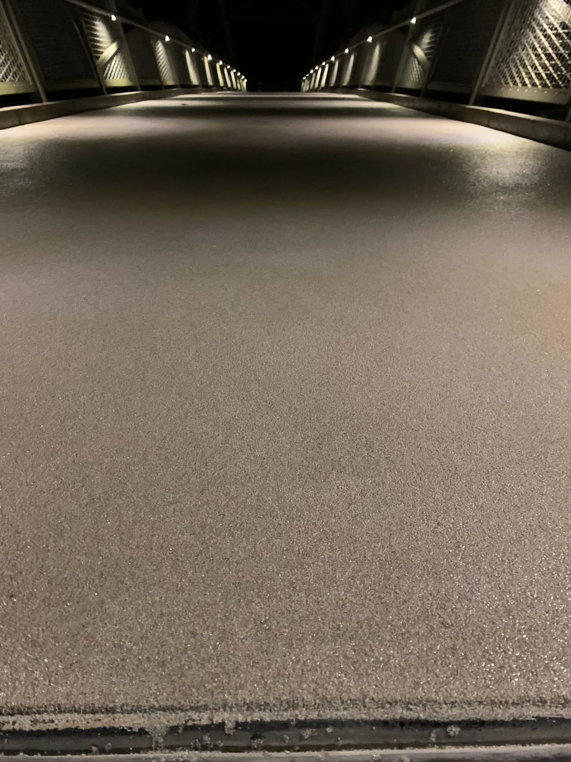 Long, illuminated bridge deck at night, covered in what appears to be ice.