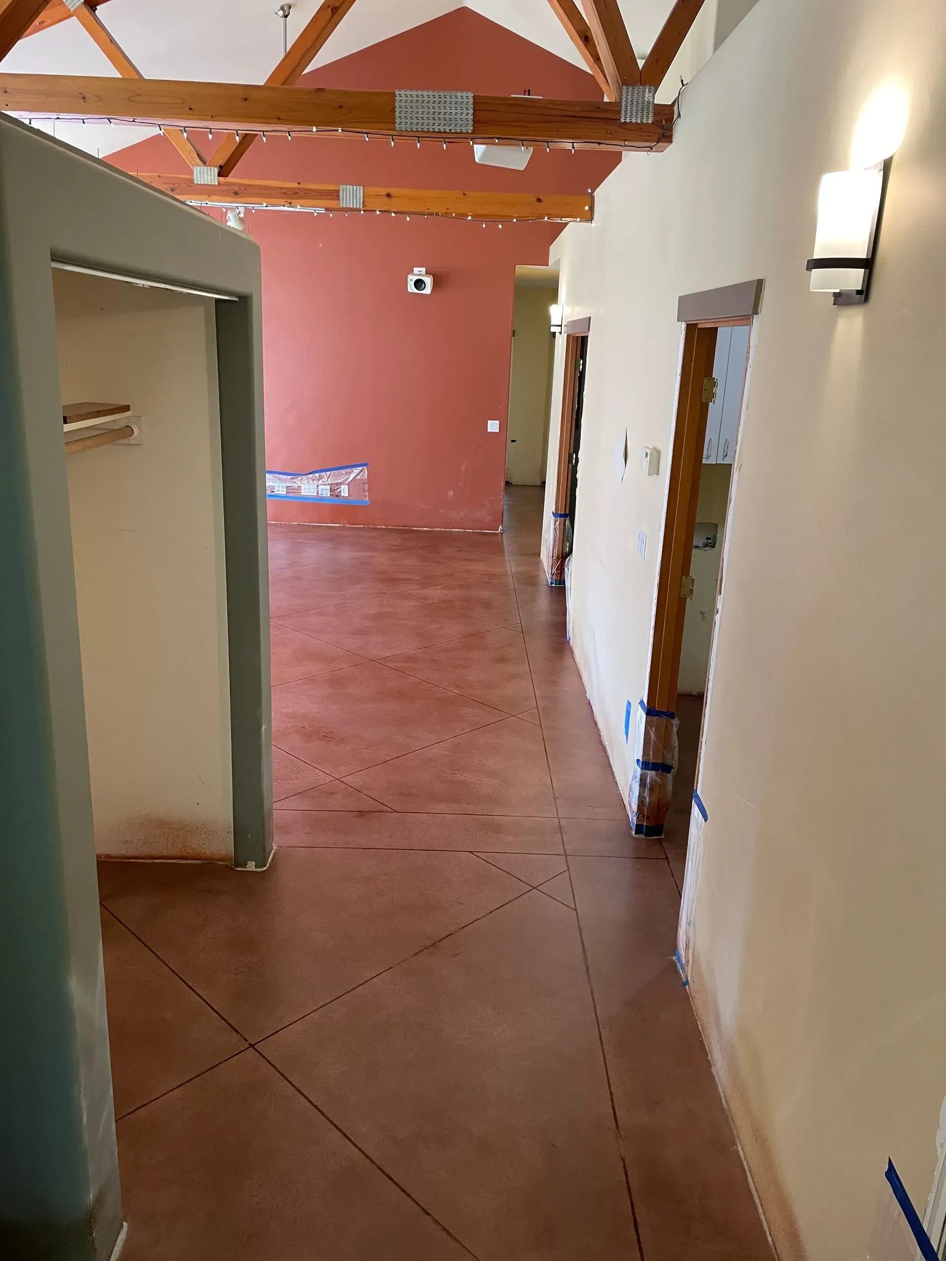 Interior hallway with brown stained concrete floor, doorways, and exposed wood beams.