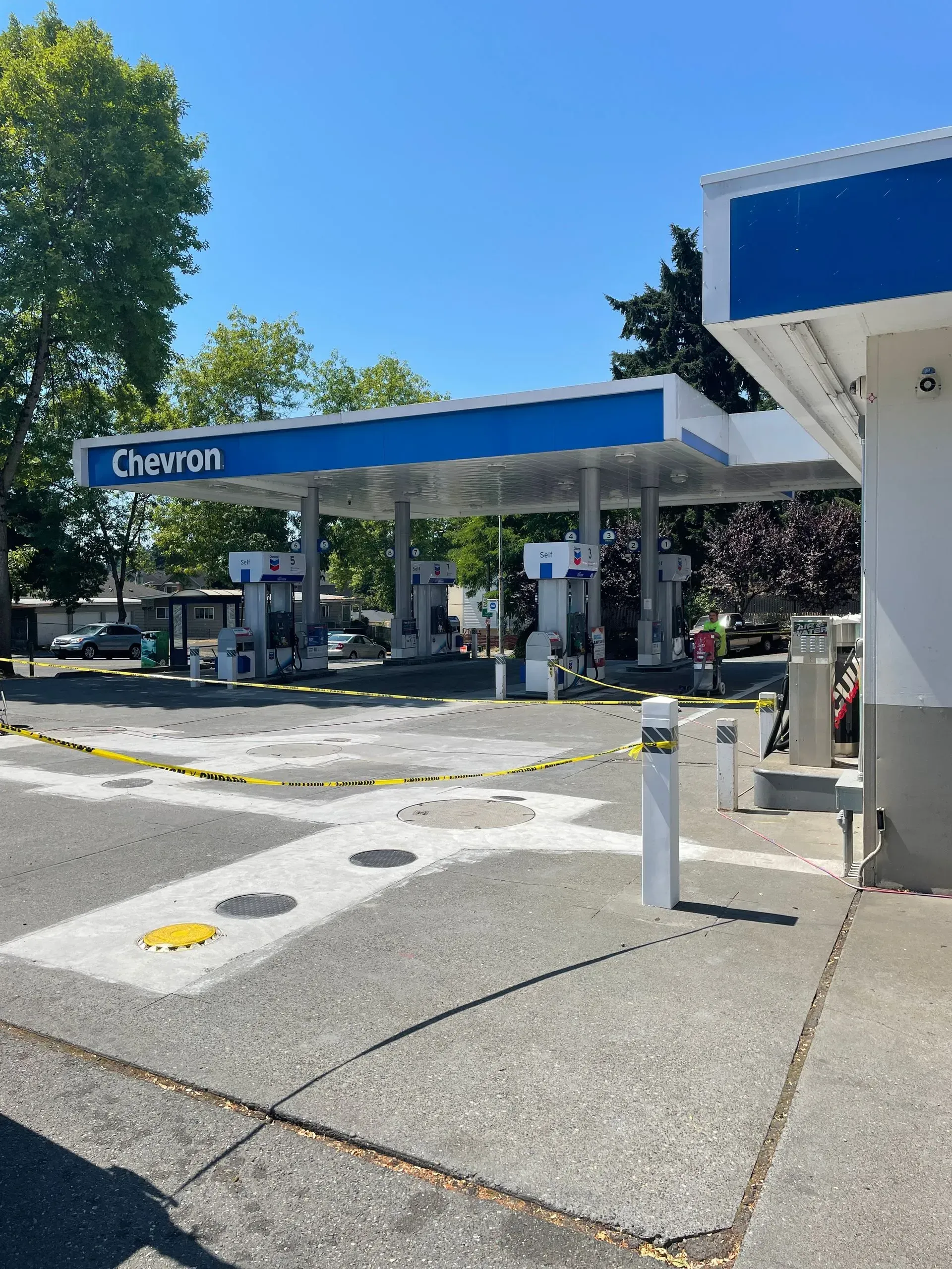 Chevron gas station with blue canopy and caution tape.