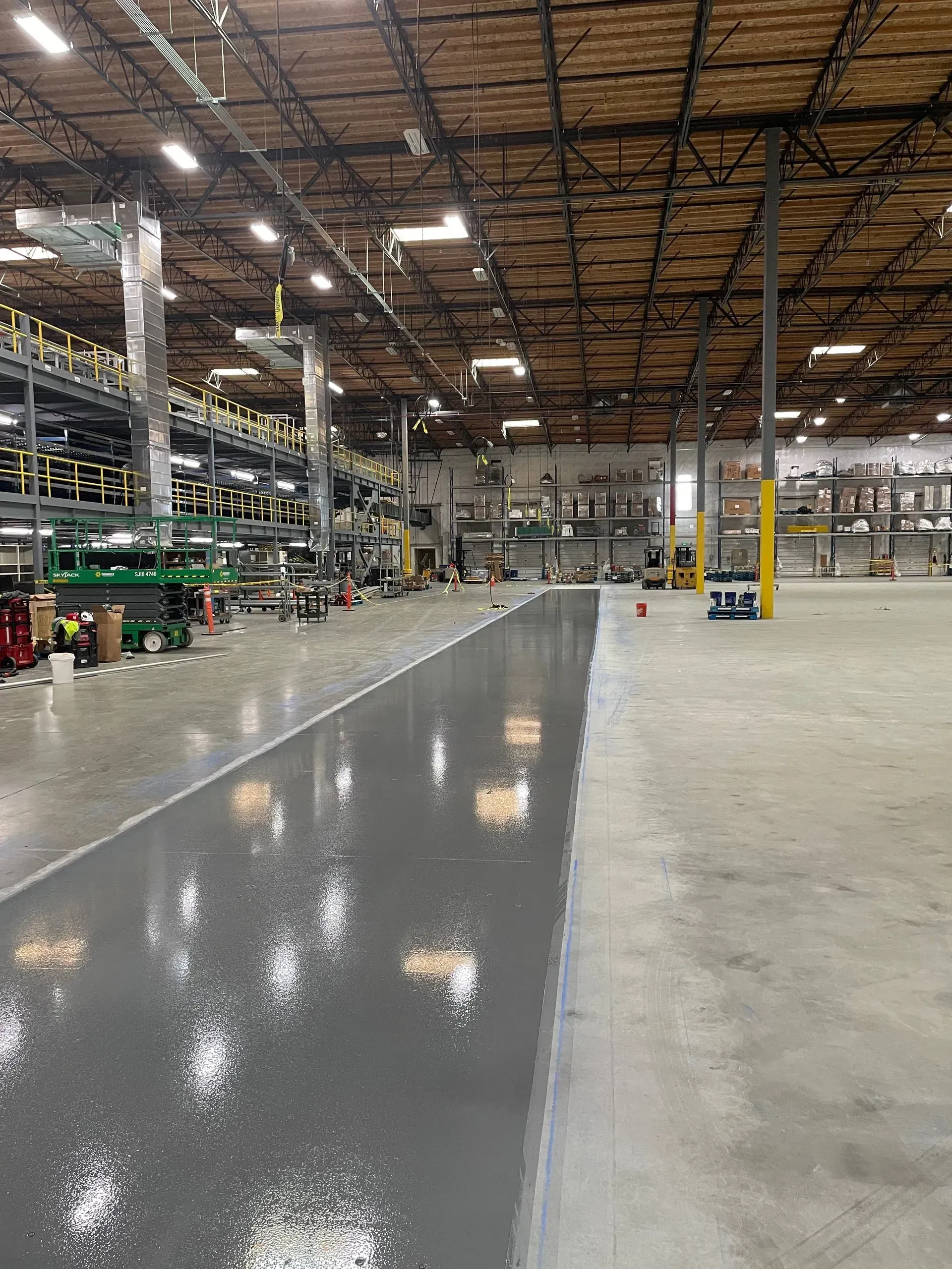Warehouse interior with gray epoxy floor, shelving, and work areas.