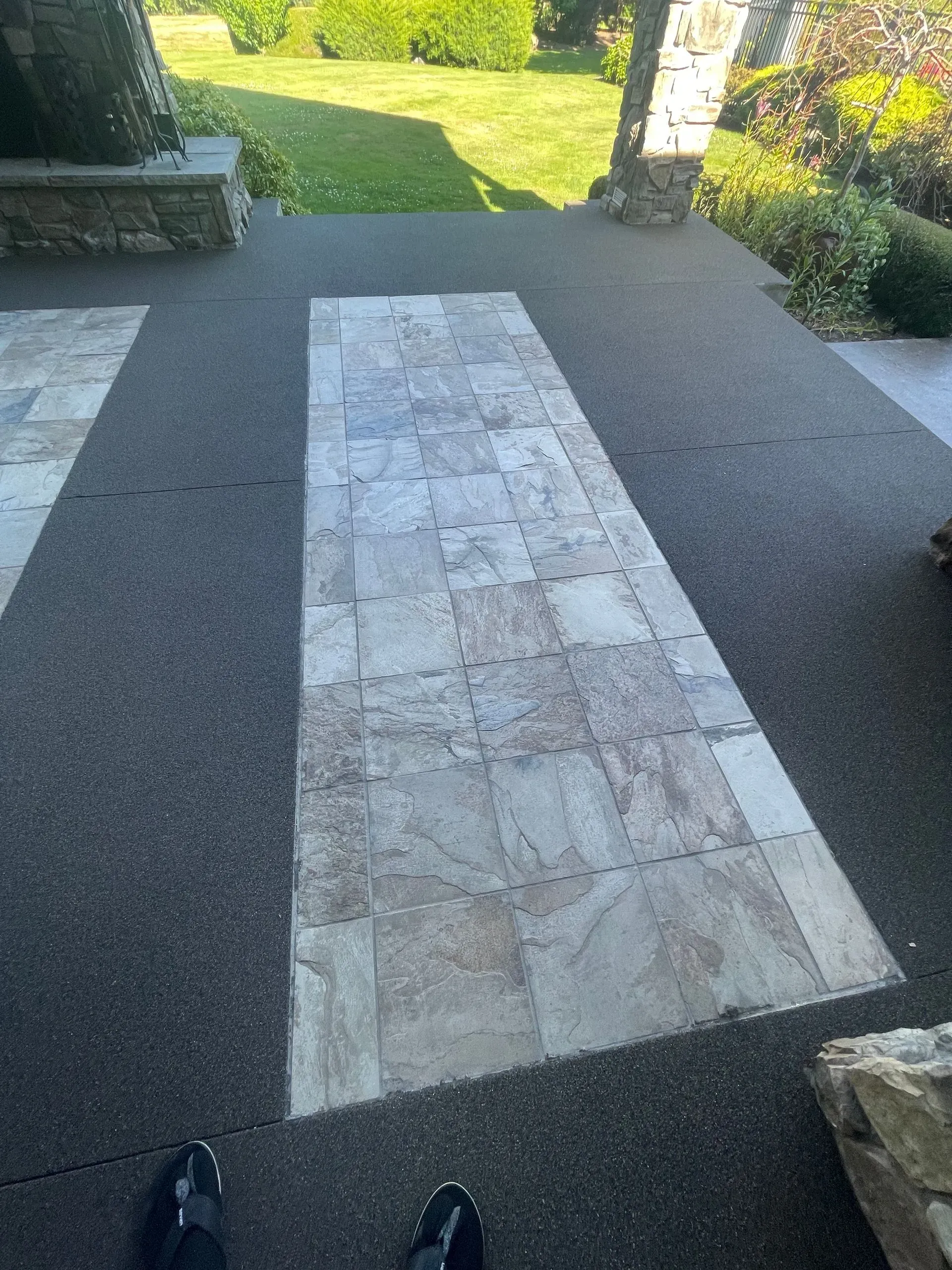 Slate tile path on dark gray patio, leading to a lawn. Black shoes visible.