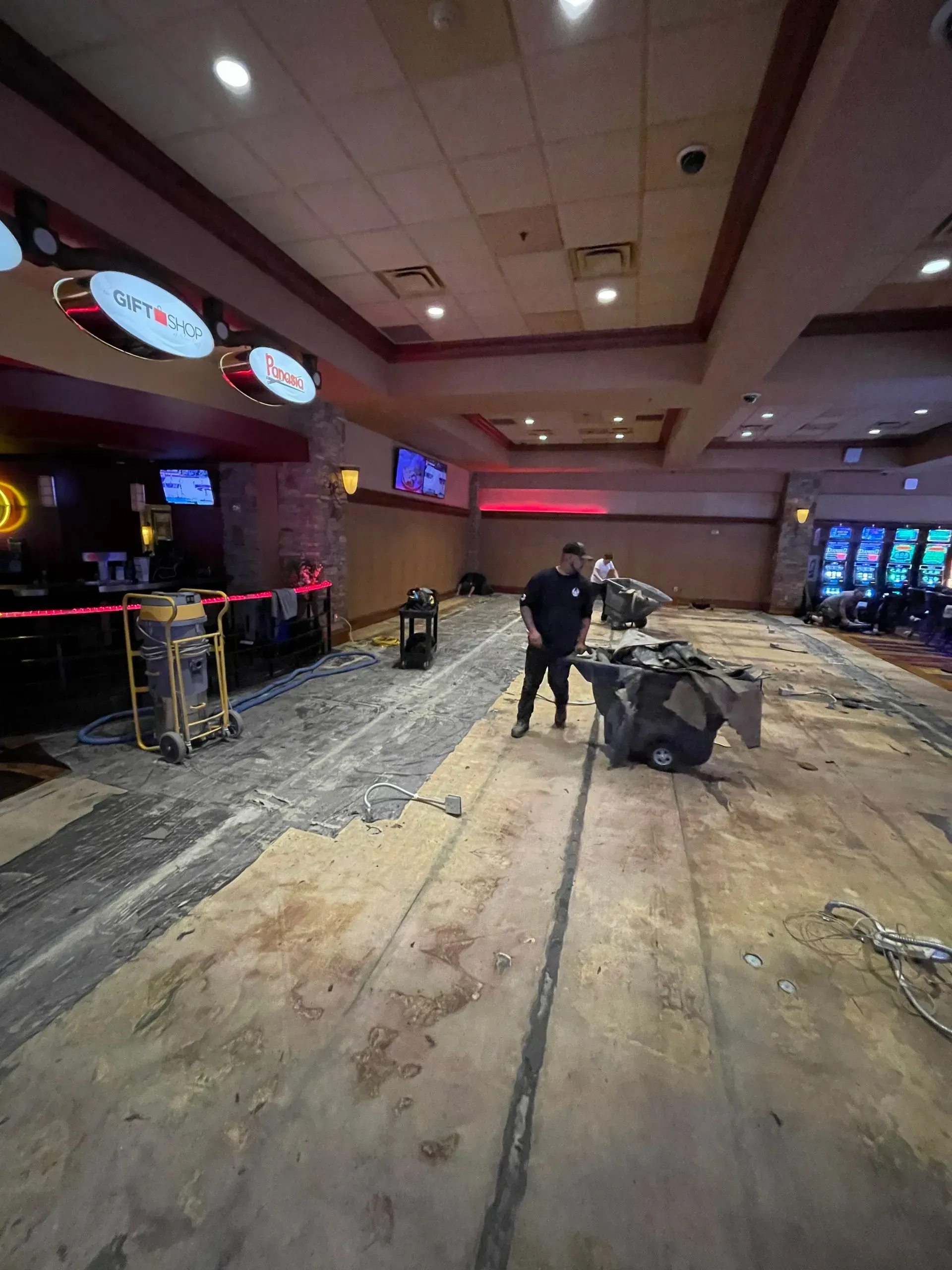 Casino floor undergoing construction, worker standing.  Flooring is removed, revealing subfloor.