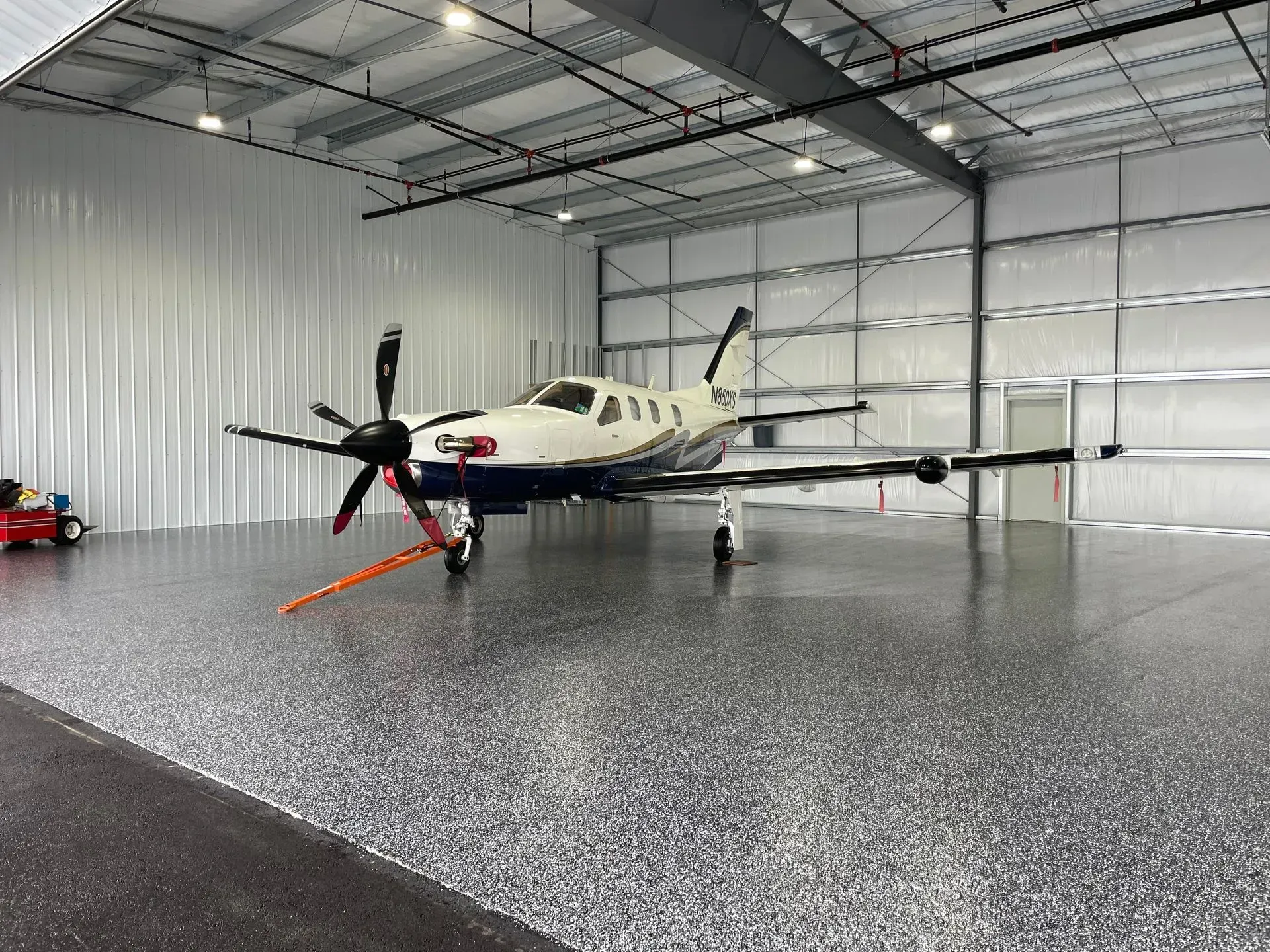 Airplane inside a metal hangar with a reflective epoxy floor.