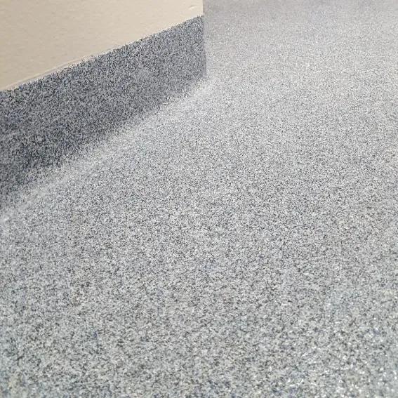 Blue speckled flooring and baseboard against a white wall.