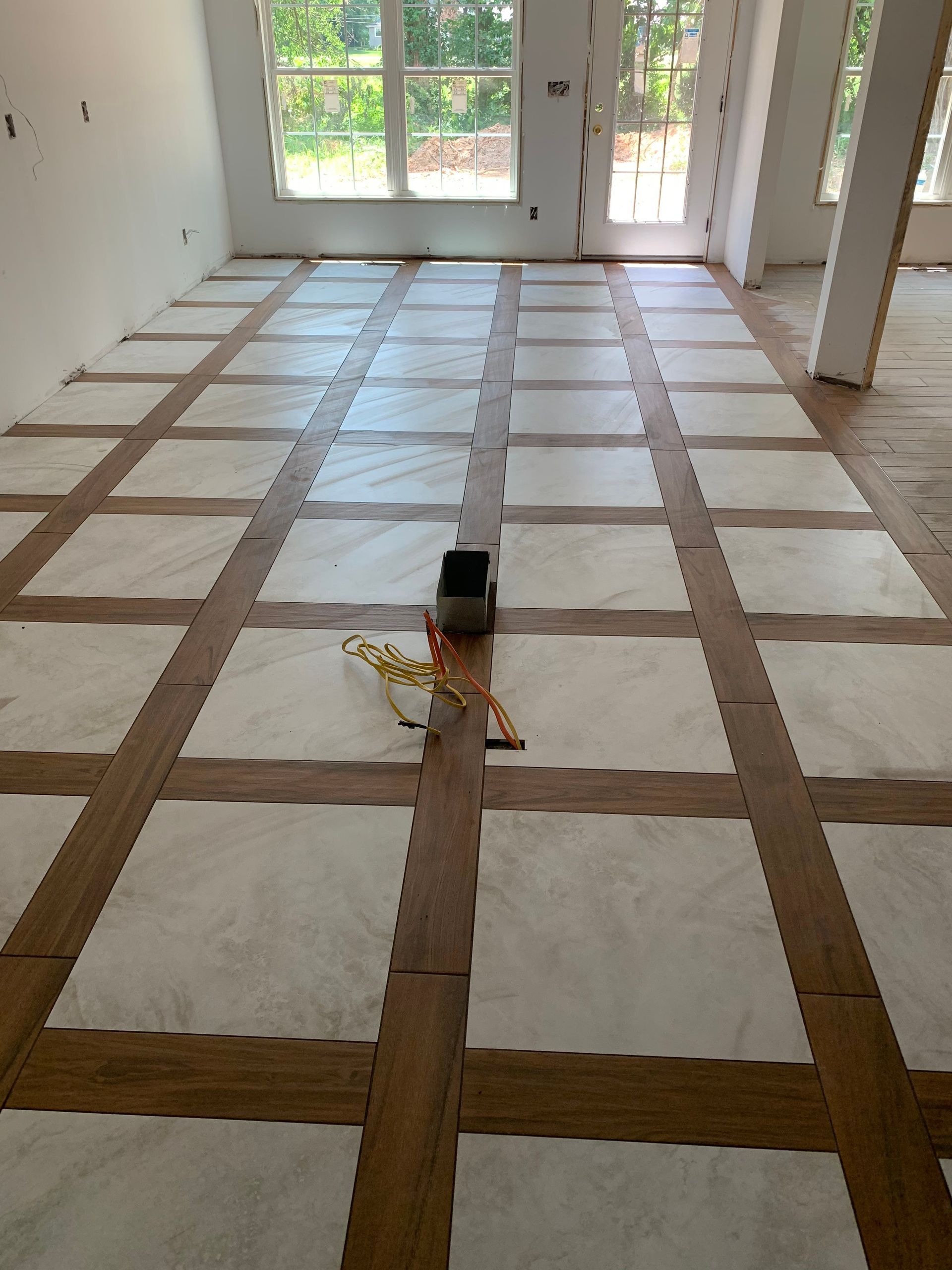 Wooden floor tile installation in progress with protective paper squares.