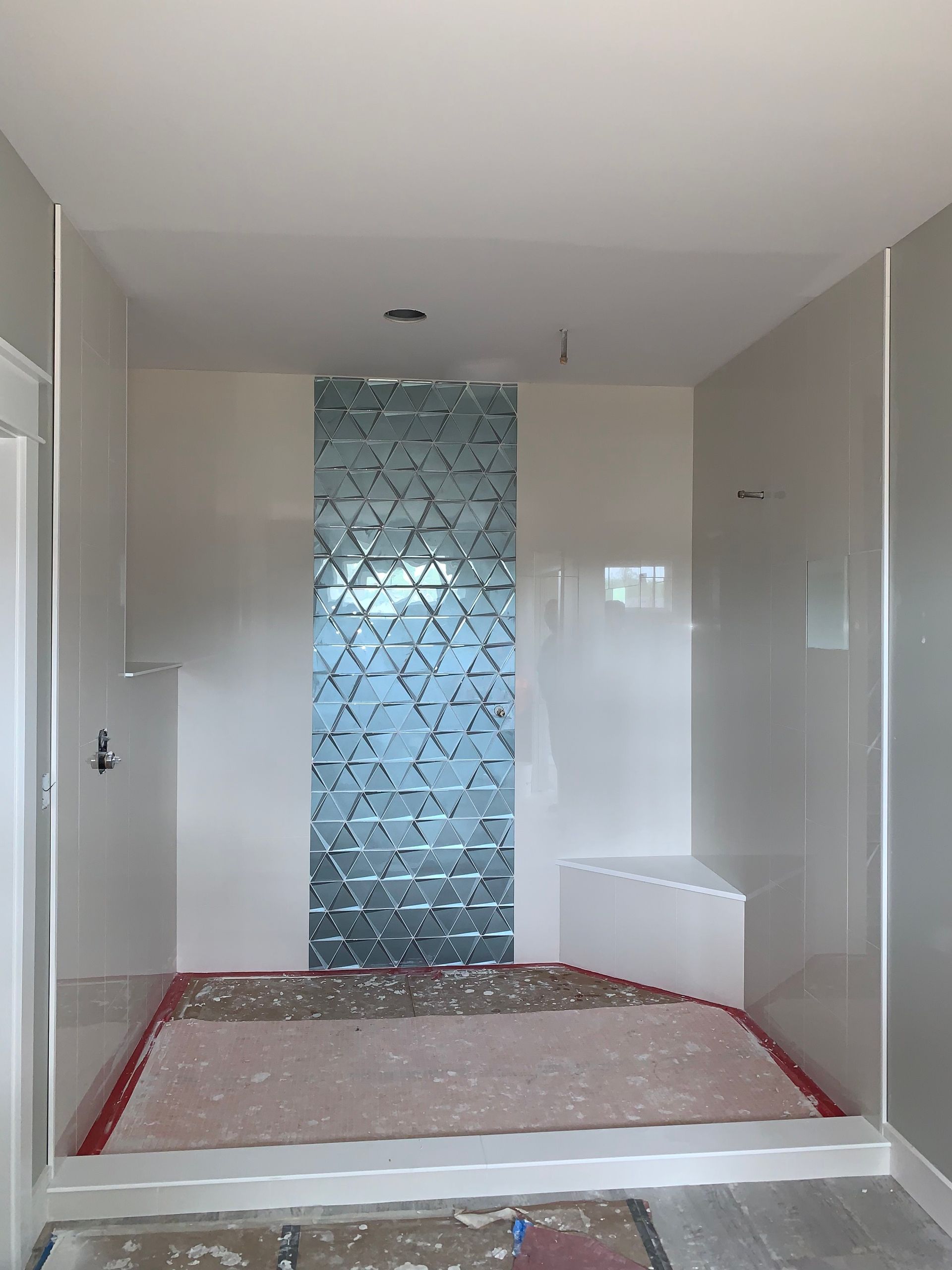 Bathroom under construction with a blue geometric tile accent wall.