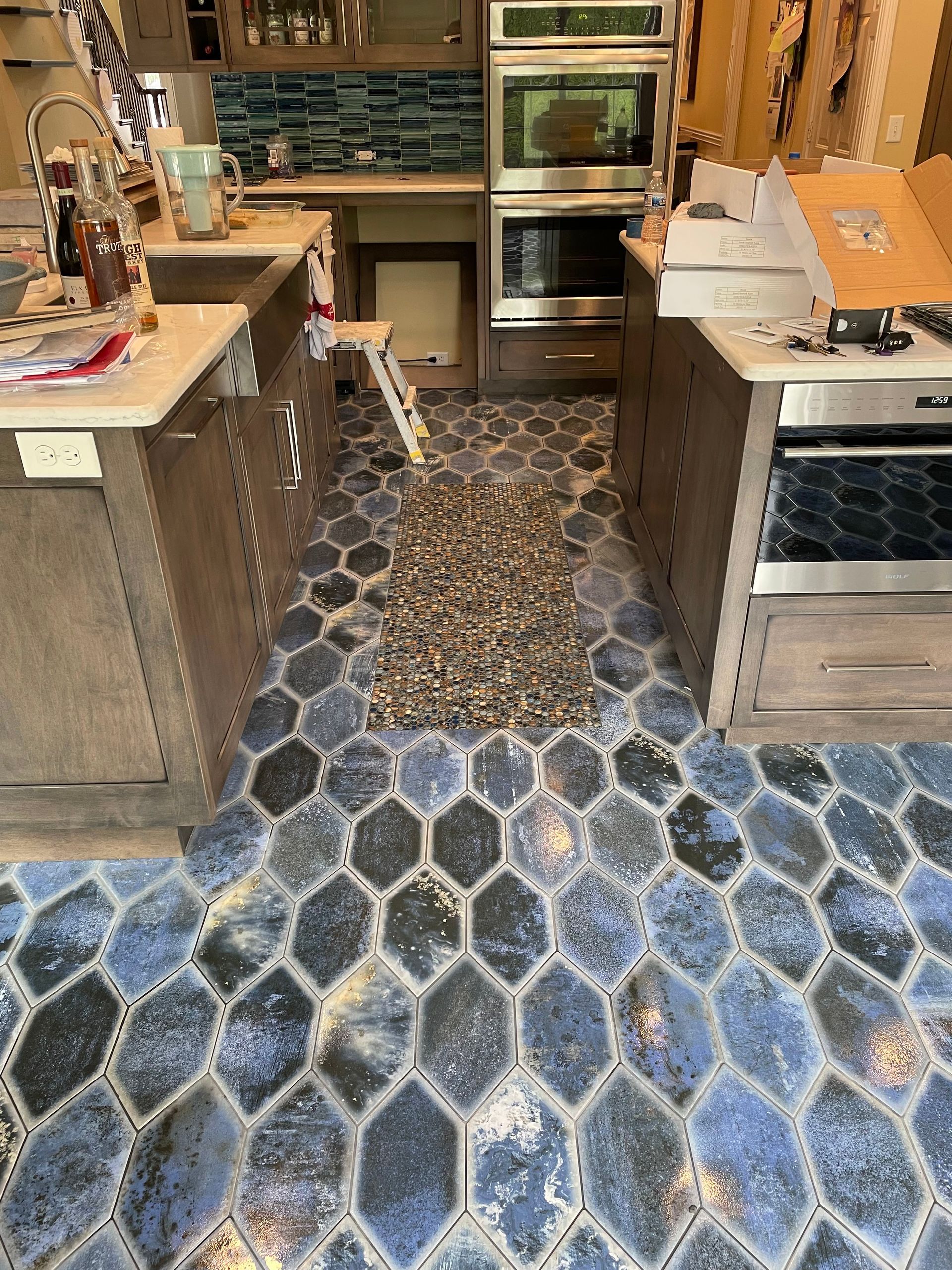Kitchen with blue patterned floor, wooden cabinets, and double oven.