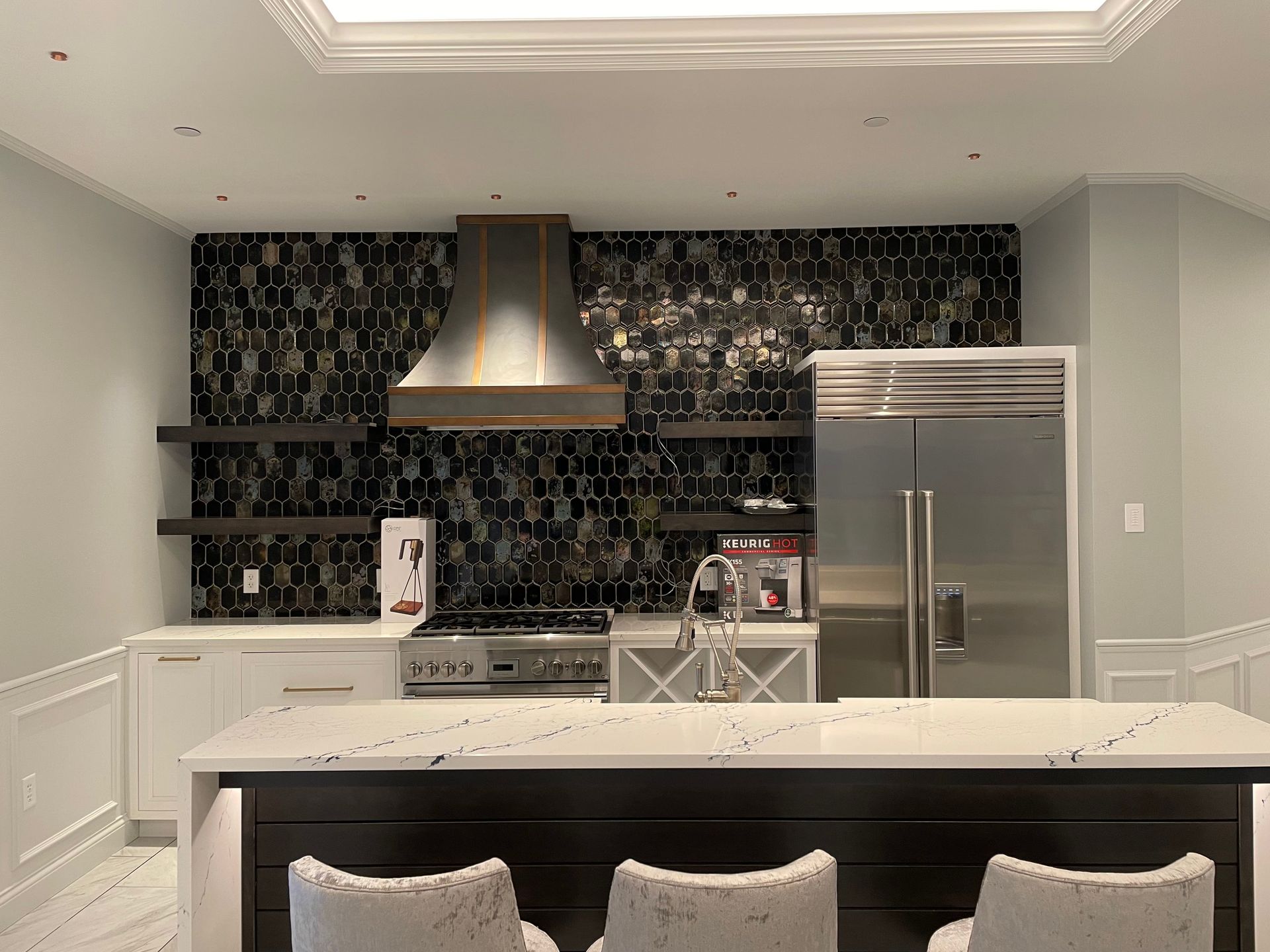 Modern kitchen with dark backsplash, stainless steel appliances, and island with bar stools.