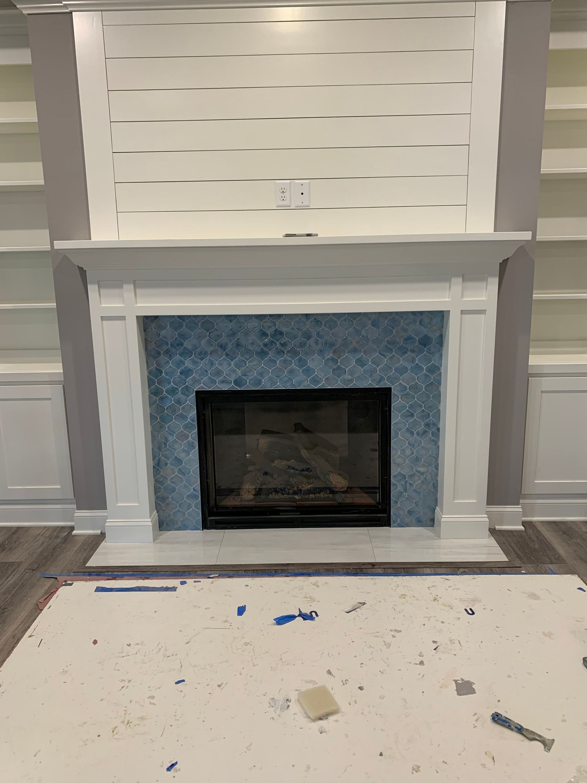 Fireplace with blue tile surround, white mantel, and built-in bookshelves.