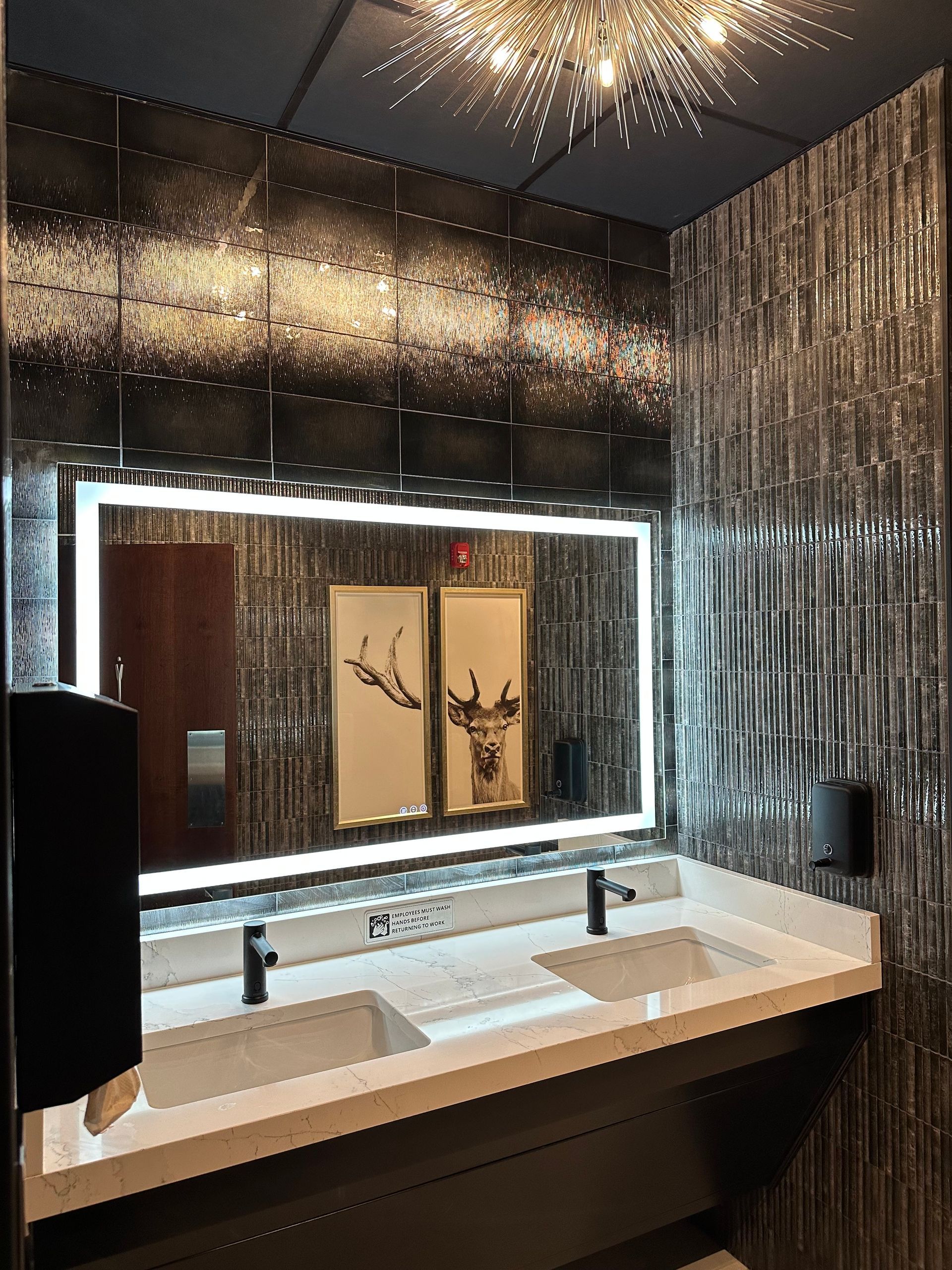 Modern bathroom with large mirror, two sinks, and decorative textured tile walls.