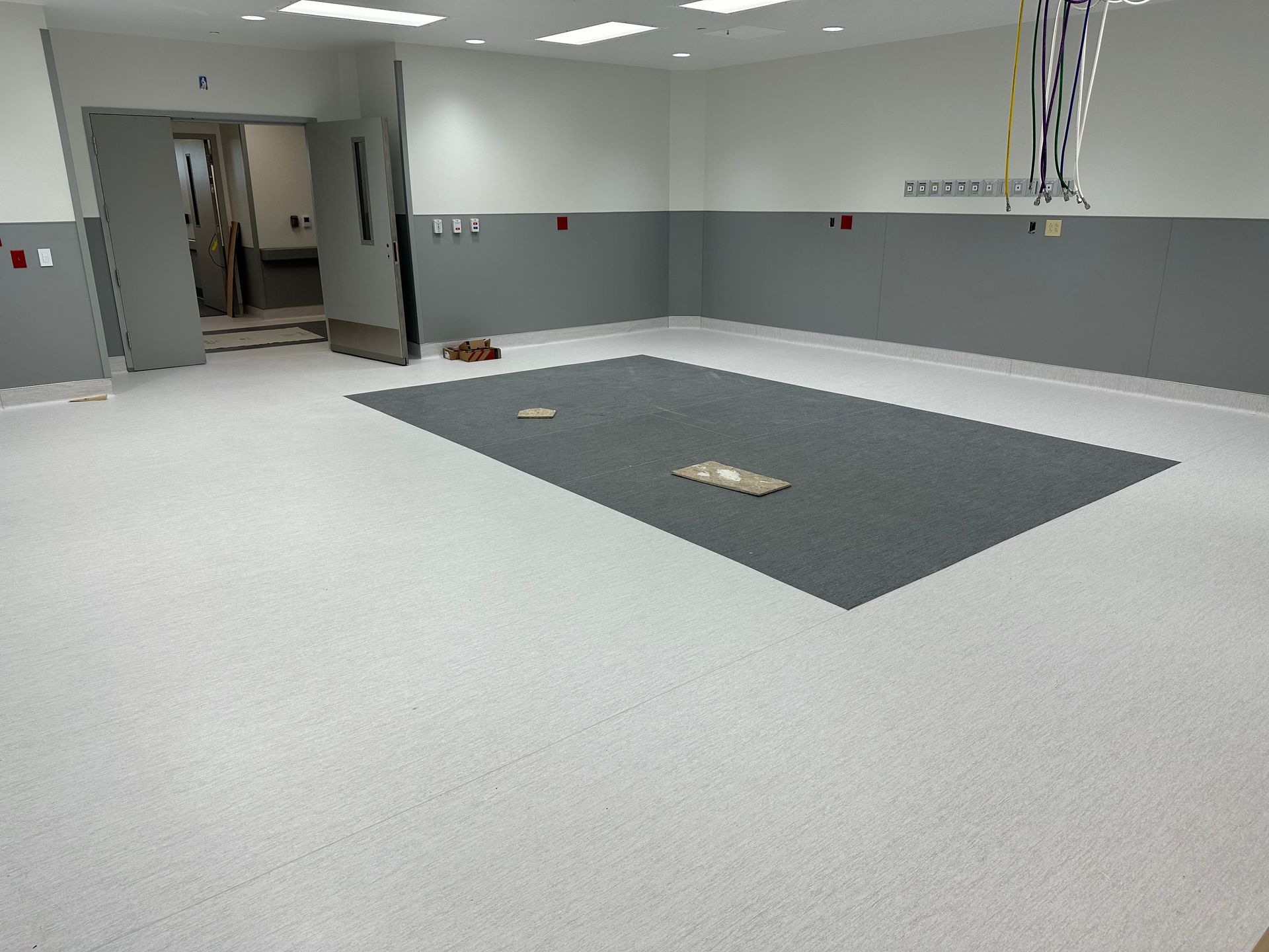 Empty, bright medical room with gray and white walls and floor, doorway visible.