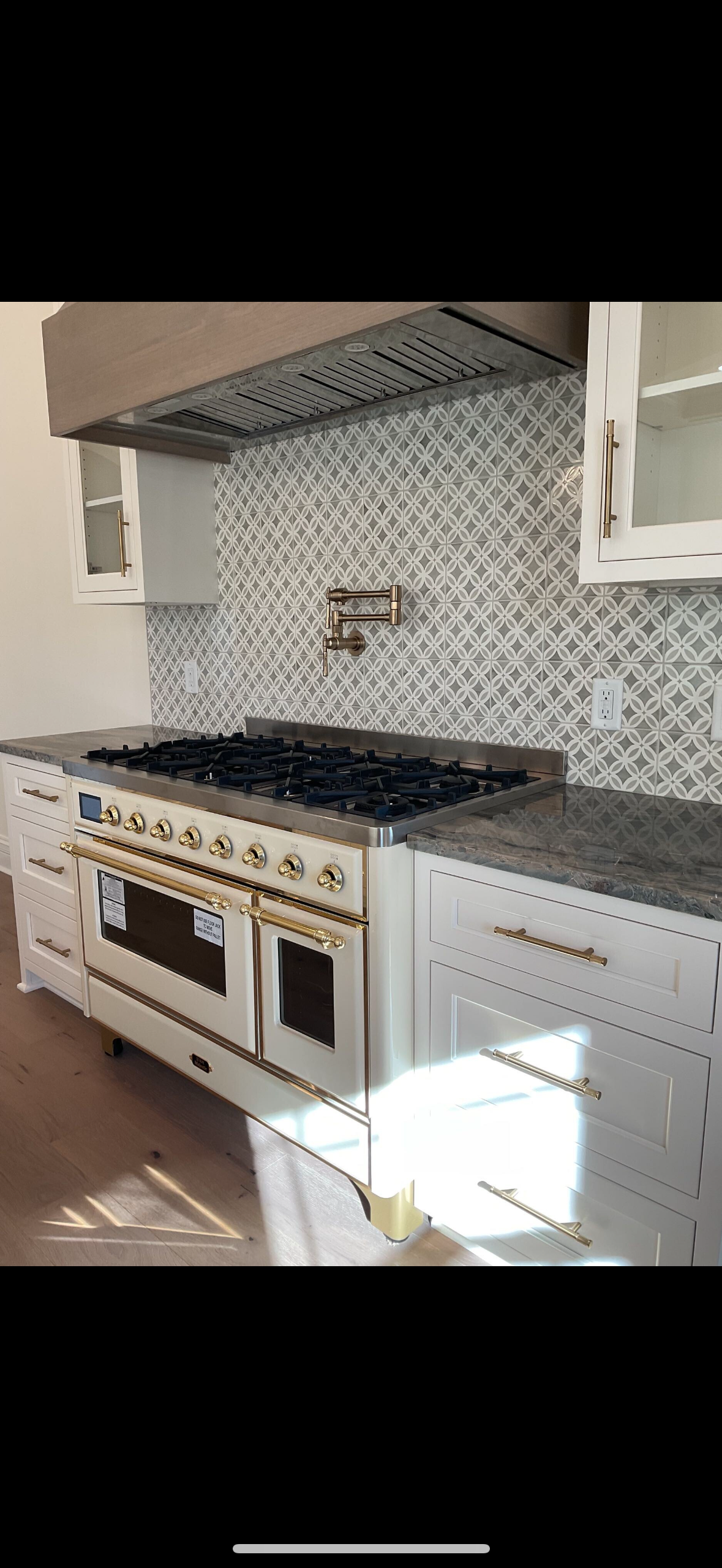 Kitchen with a white oven and range, dark stove top, tile backsplash, and stainless hood.