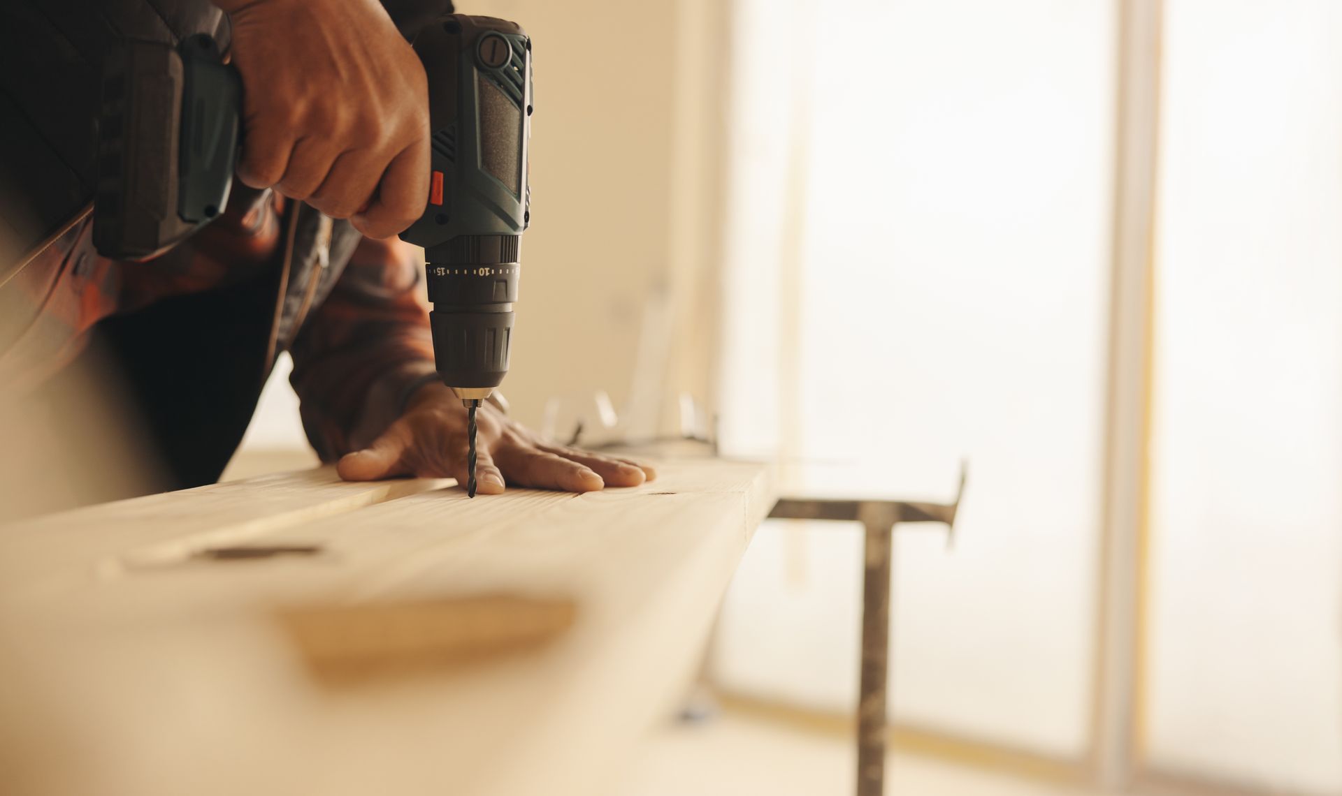 Person using a power drill on a wooden board.