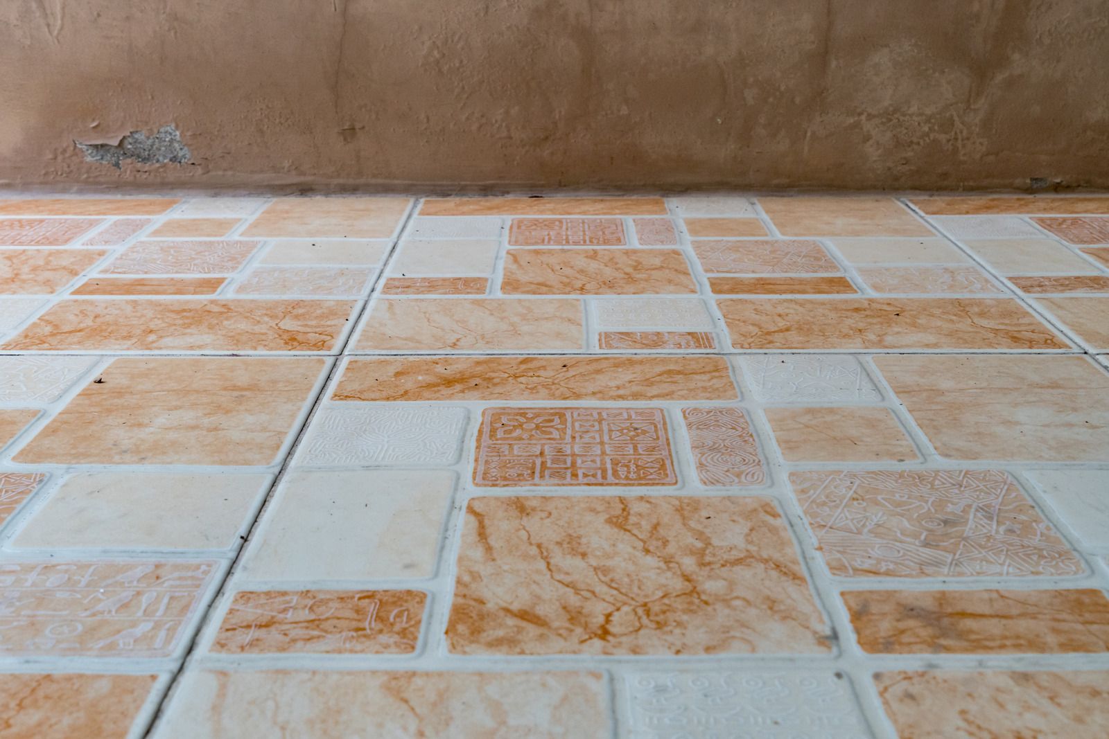 A close up of a tiled floor with a brown wall in the background.