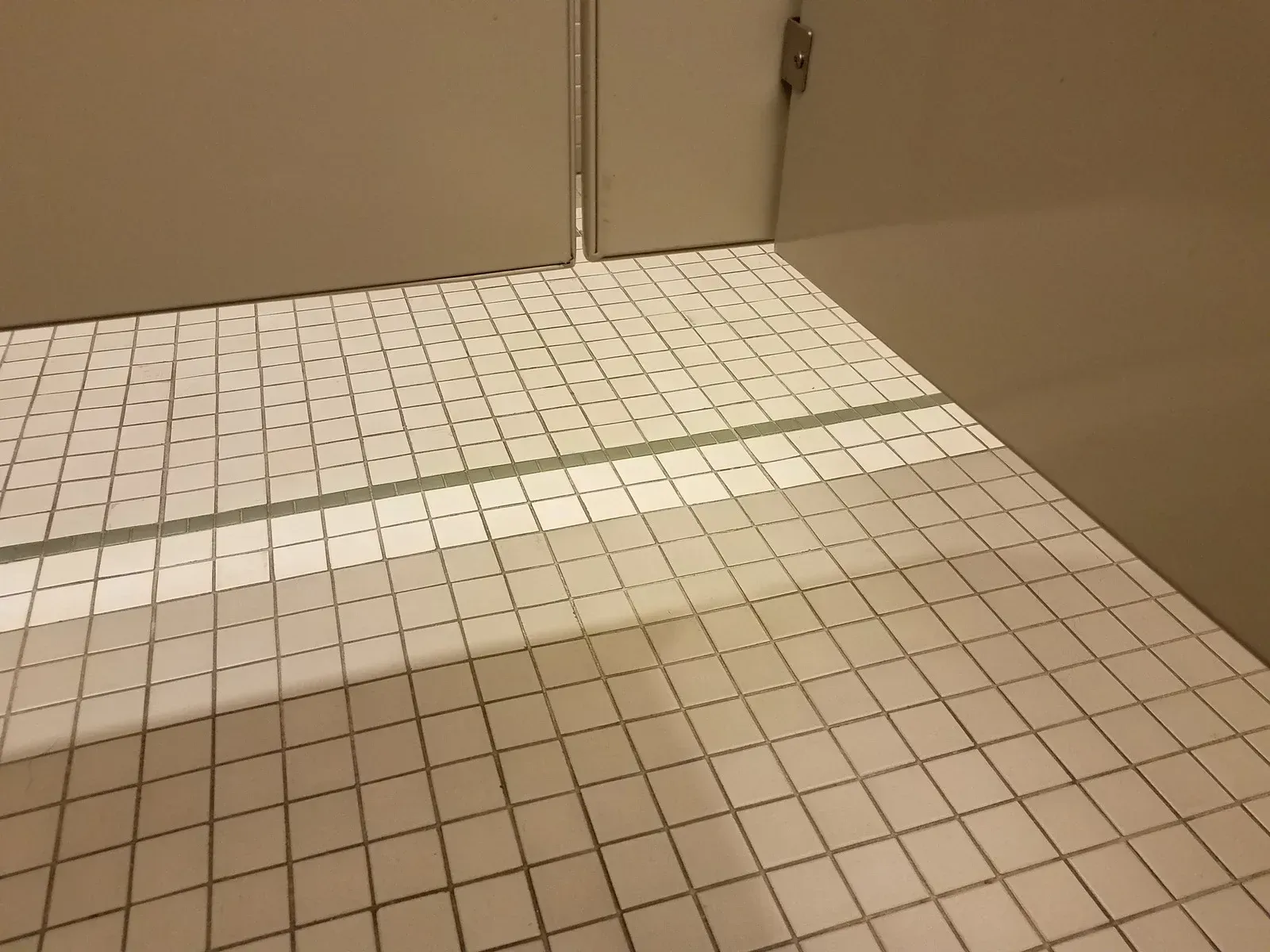 A bathroom with white tiles and a mirror on the floor