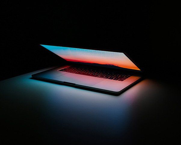 Half open laptop glows in darkness