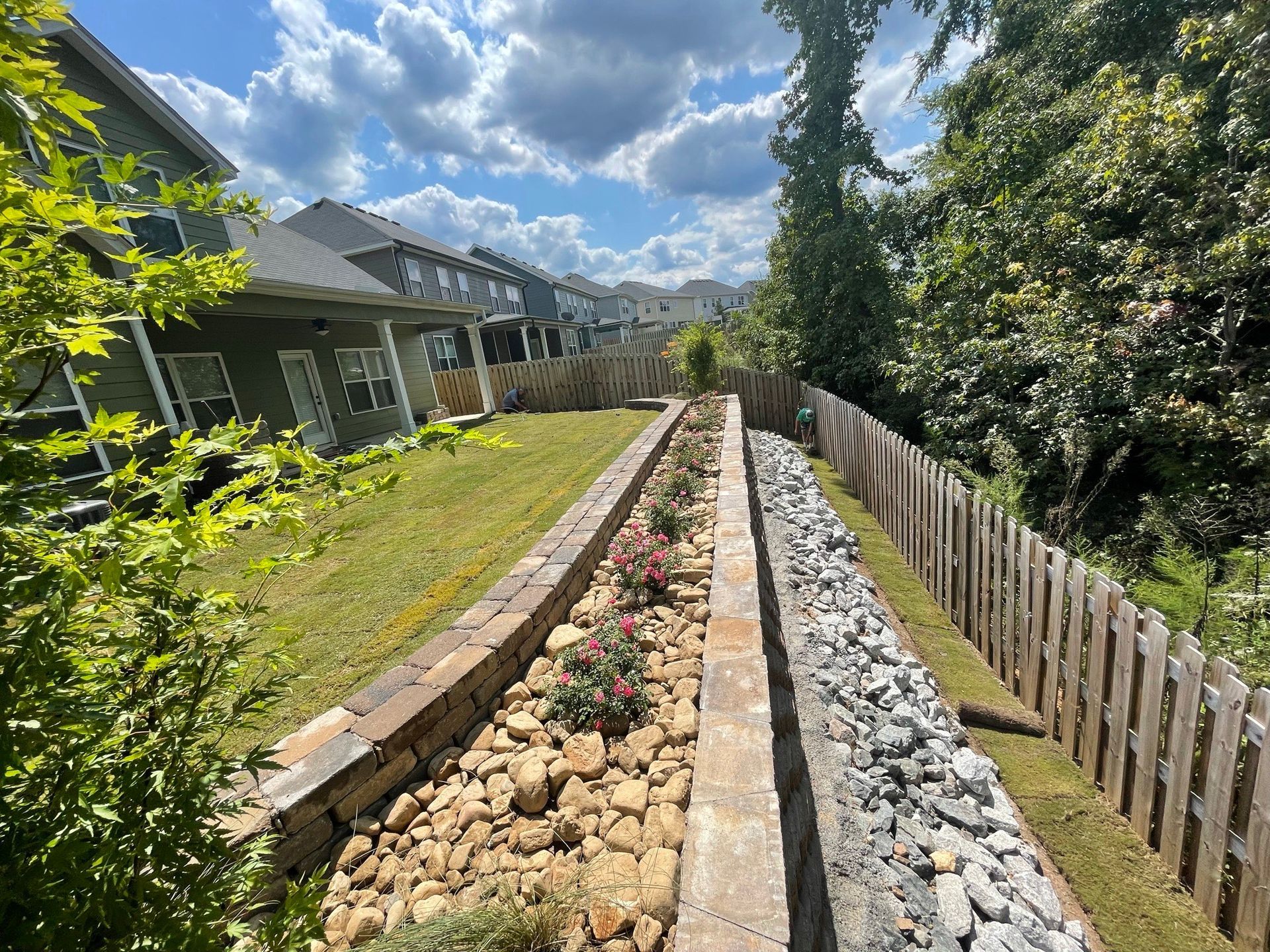 A brick walkway leading to a house with a wooden fence.