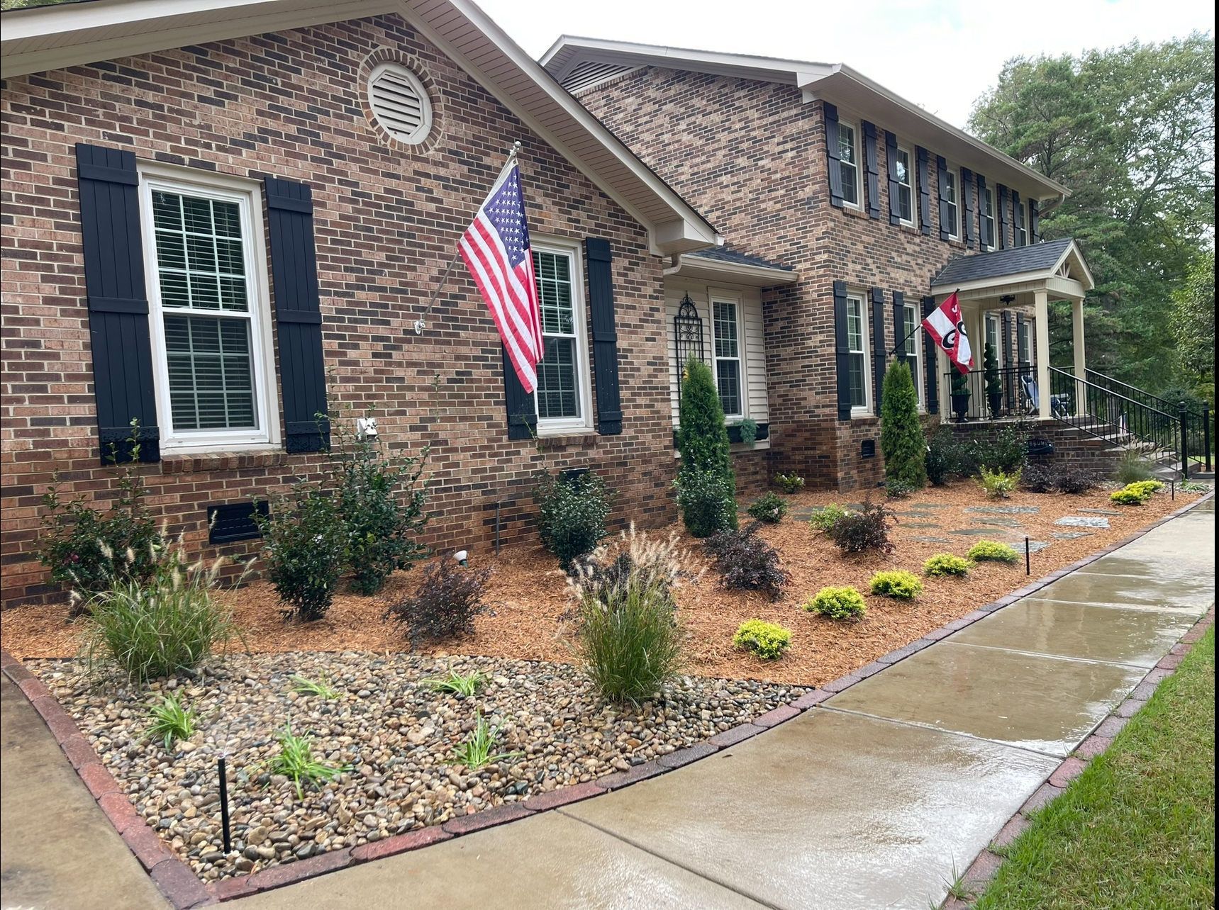 Brick house with landscaped yard; American flag hangs from the window.