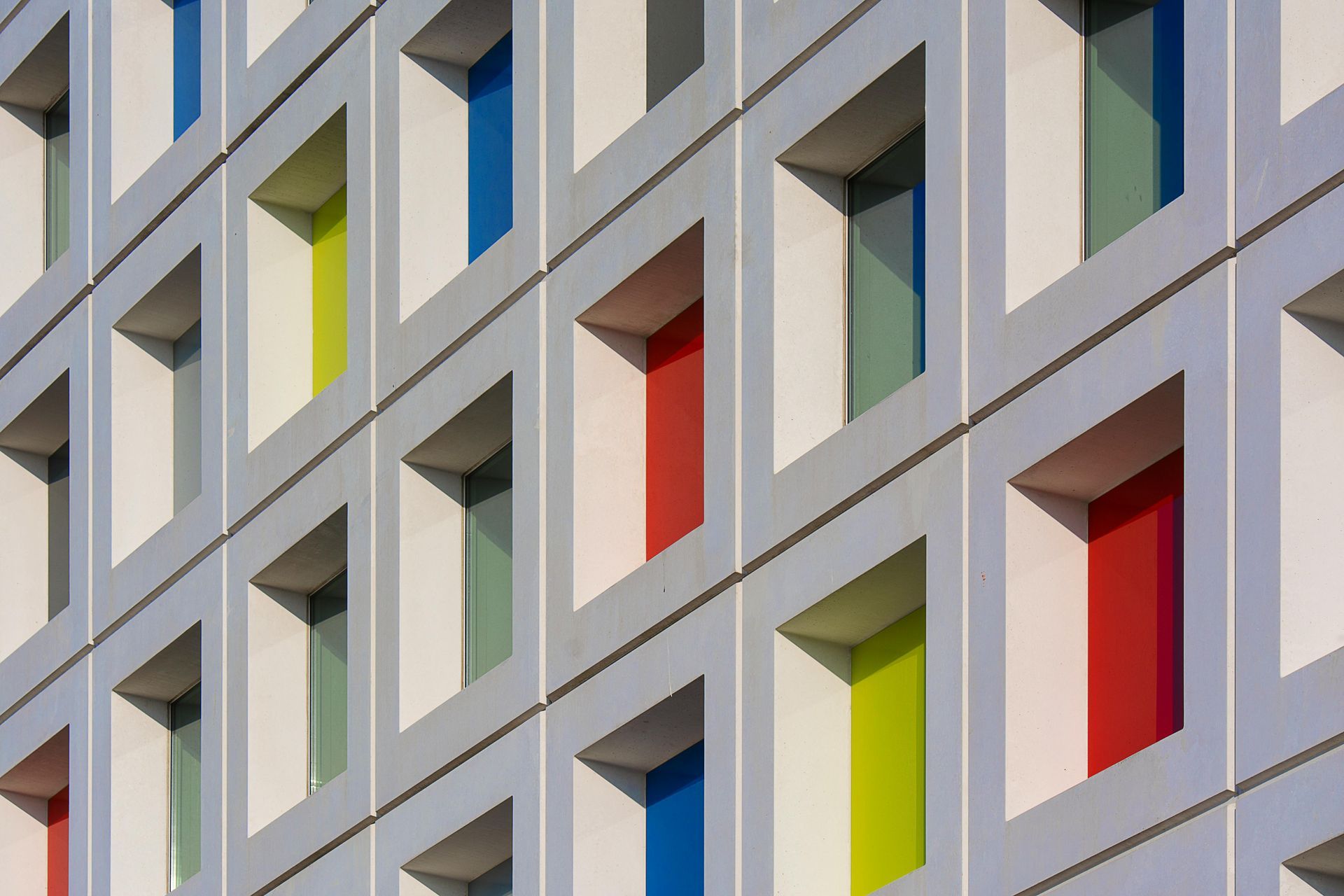 Building facade with rectangular openings, showcasing colorful interior walls: blue, red, green, and yellow.