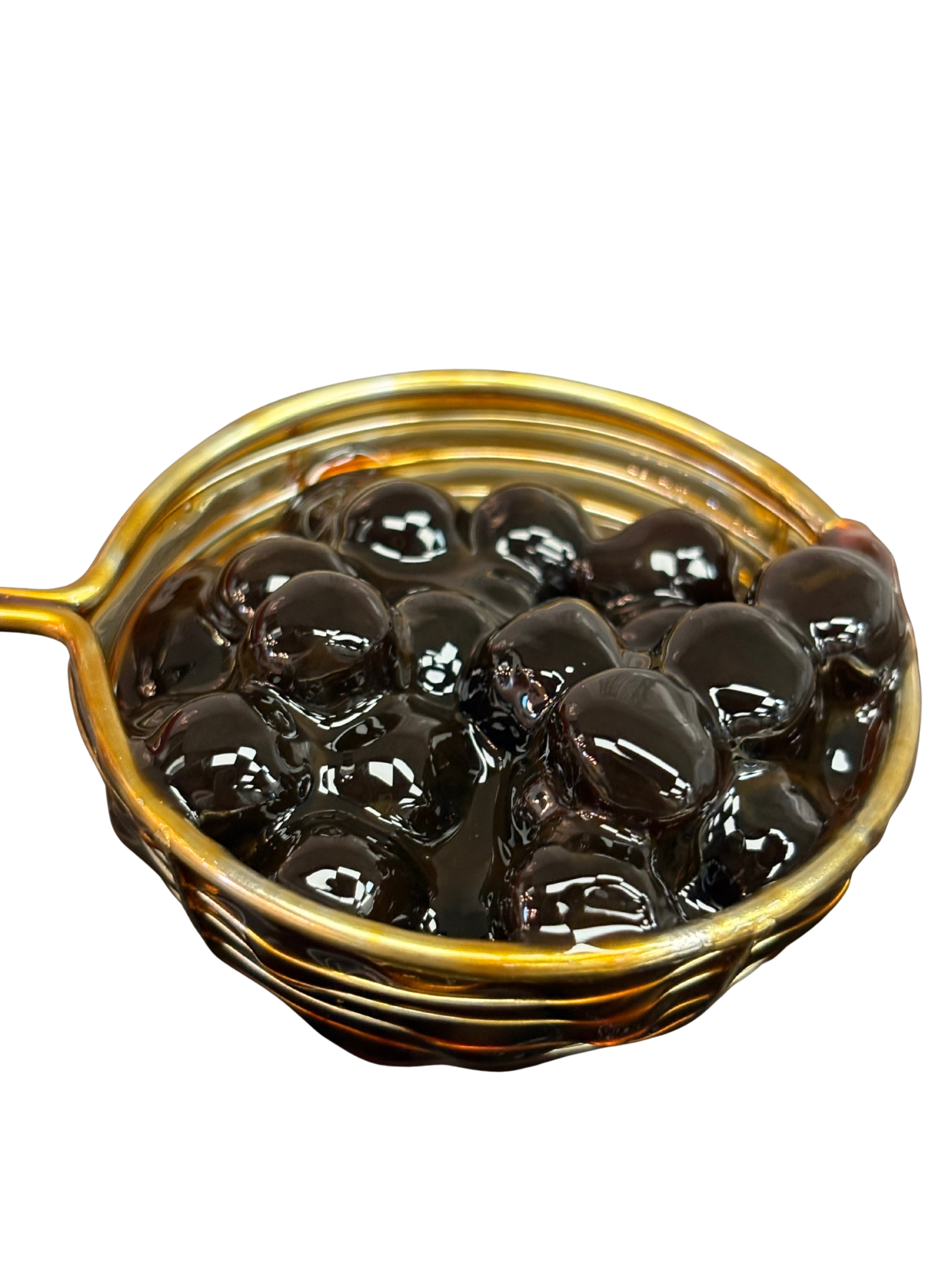 Dark brown boba pearls in a gold strainer, against a white background.
