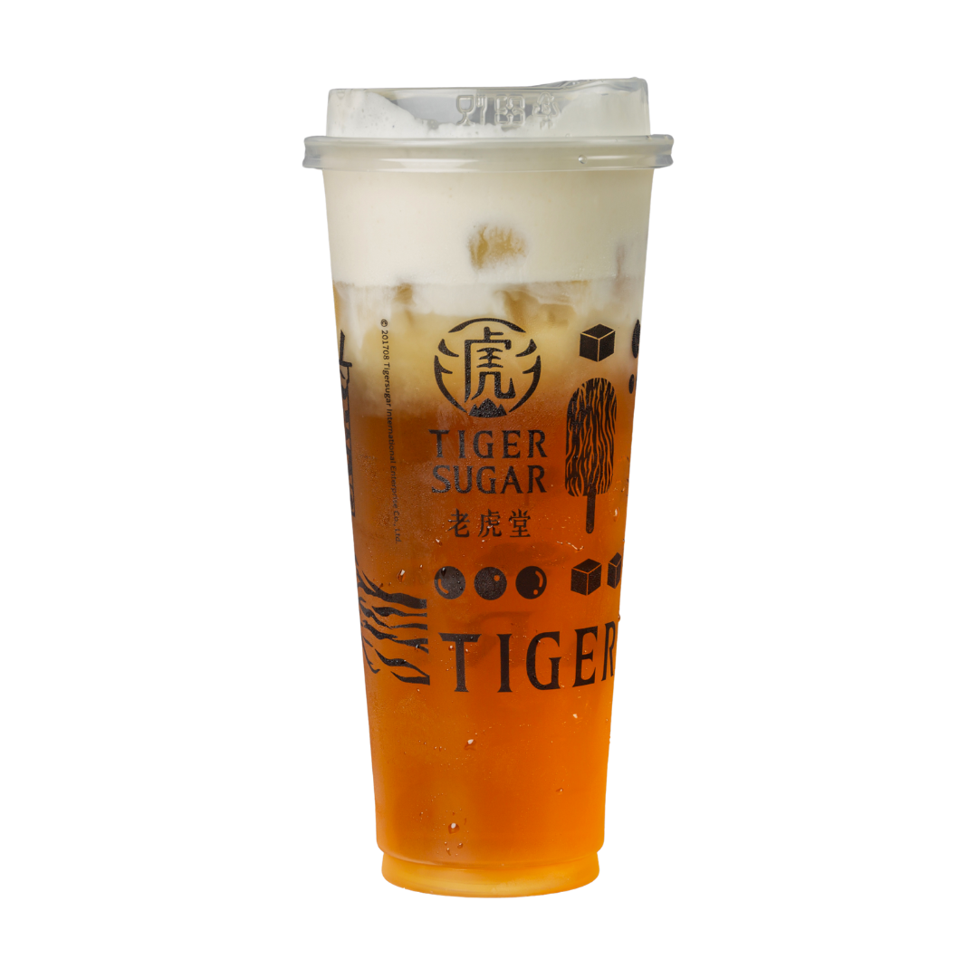 A tall, clear Tiger Sugar drink with a white cream layer, a brown tea base, and tapioca pearls at the bottom.