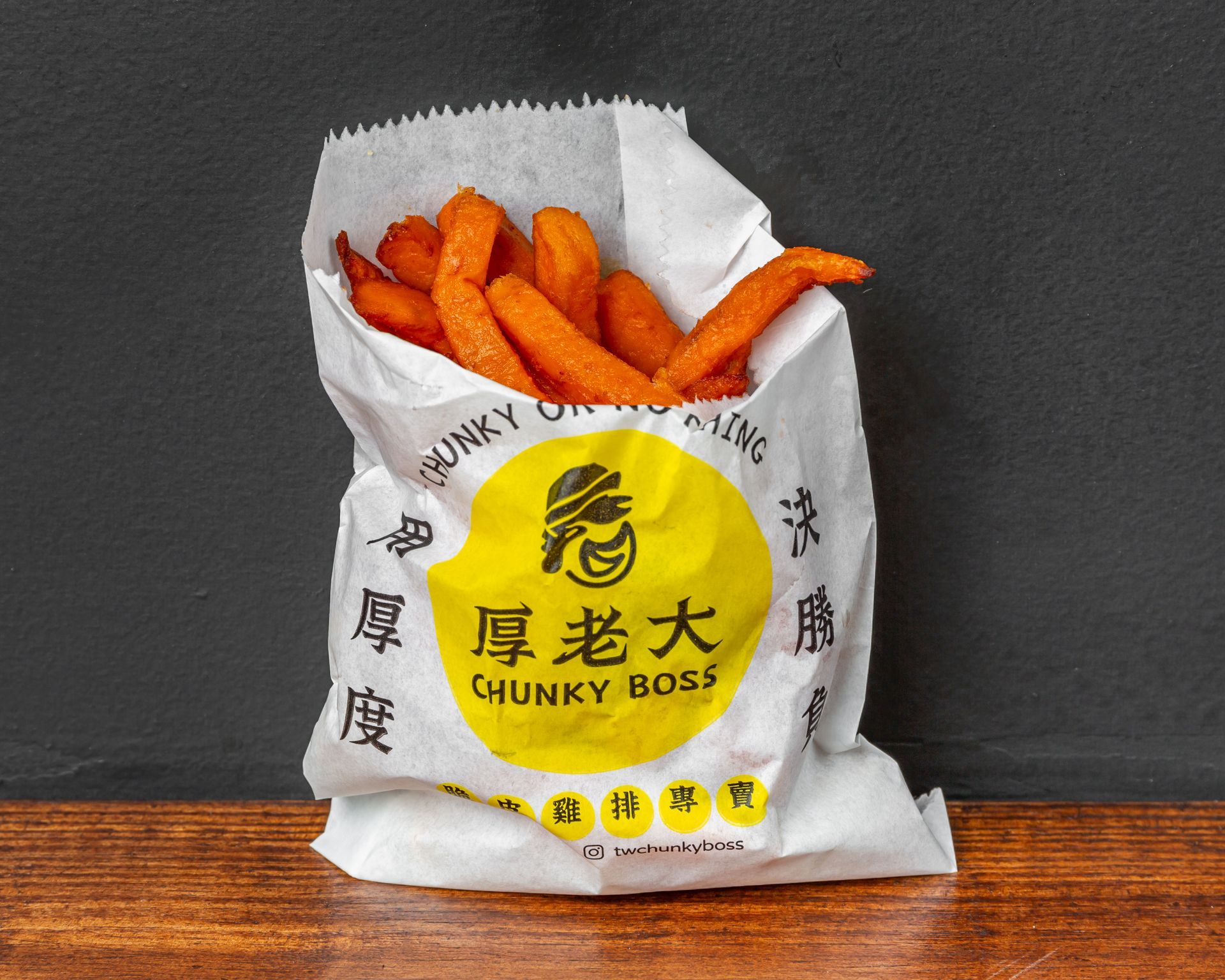 Bag of sweet potato fries from Chunky Boss on a wooden surface. The bag is white with a yellow logo and Chinese characters.