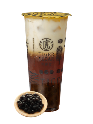Tiger Sugar boba tea with layers of brown sugar syrup, milk, and tea, in a clear cup with black tapioca pearls on a wooden plate.