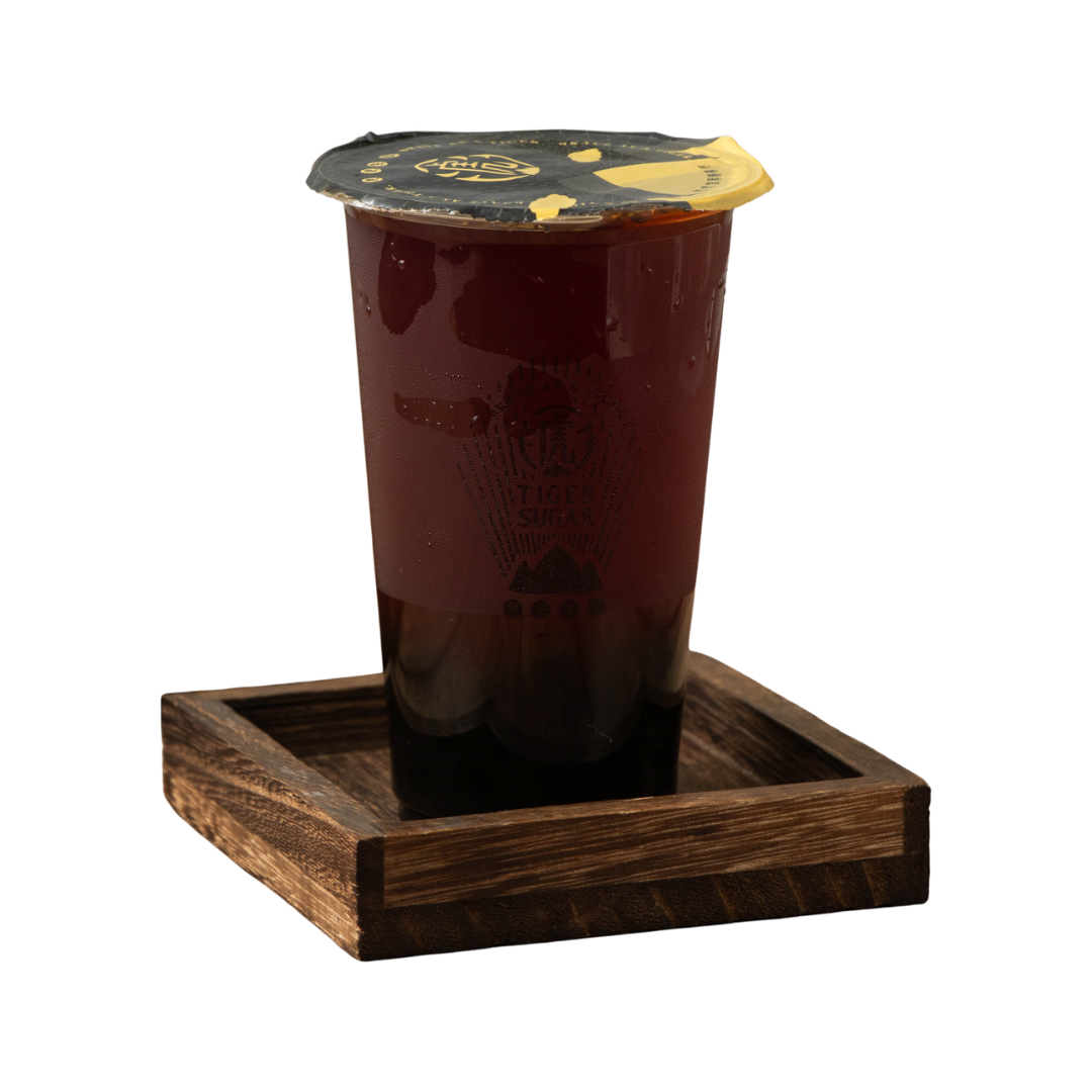 A cup of dark tea with a lid on a small wooden tray.