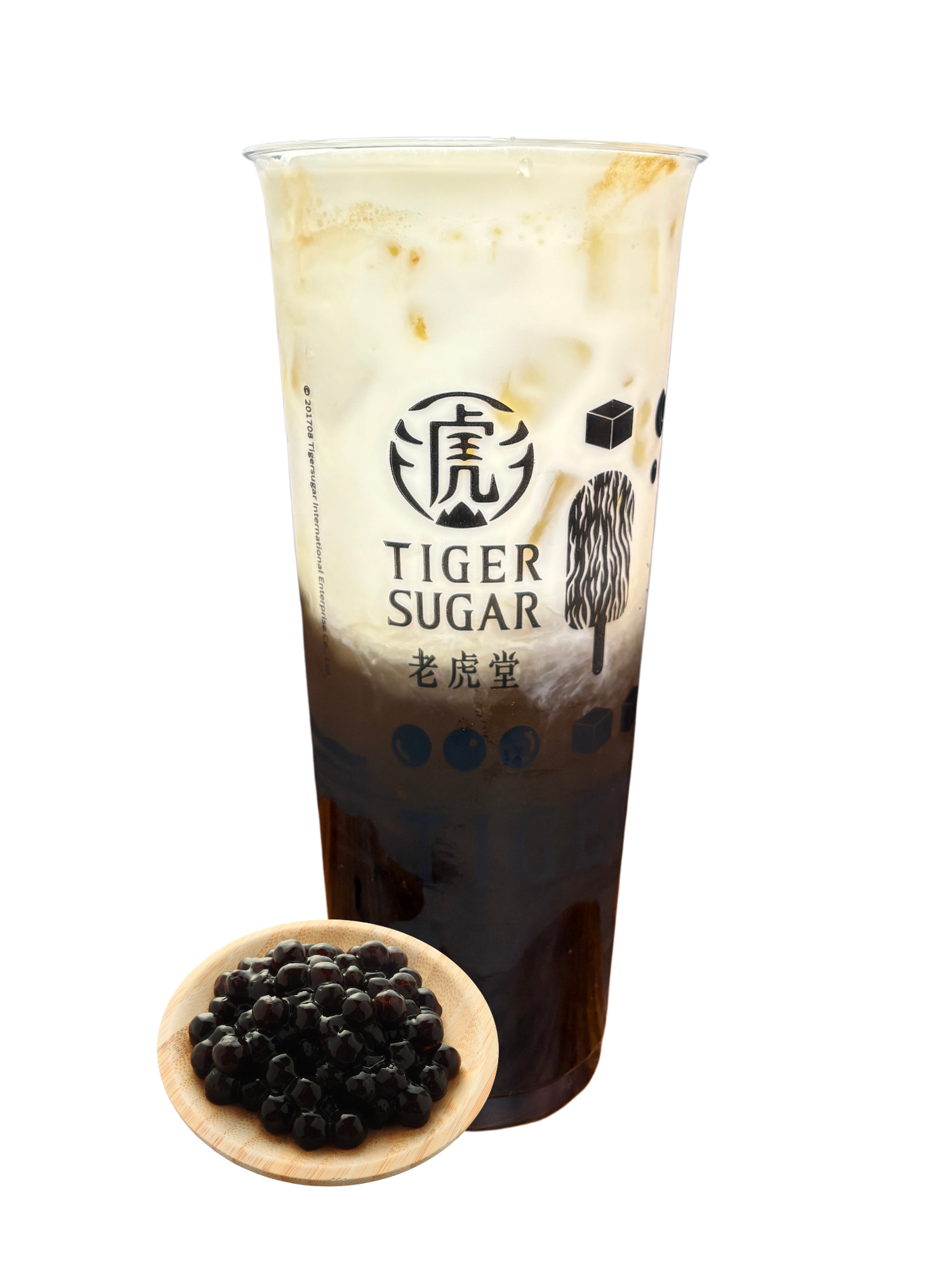 Tiger Sugar boba drink with brown sugar syrup, cream, and tapioca pearls in a clear cup with a small wooden dish of pearls.