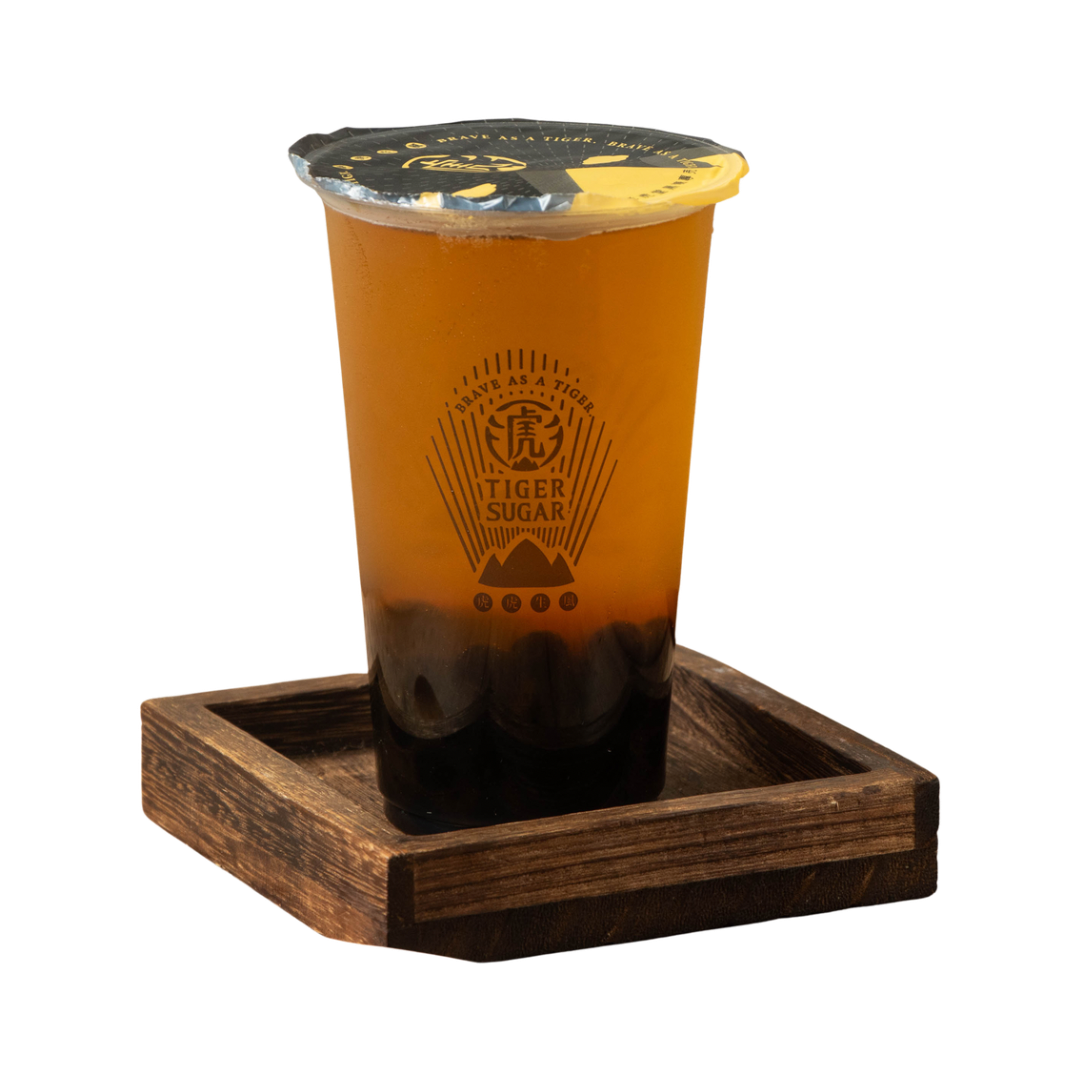 A cup of orange-colored bubble tea with dark tapioca pearls, resting on a wooden tray.