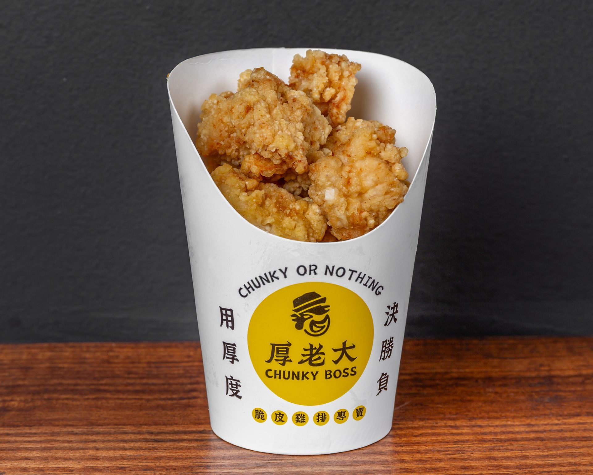 Fried chicken in a white paper cup, with the brand name 