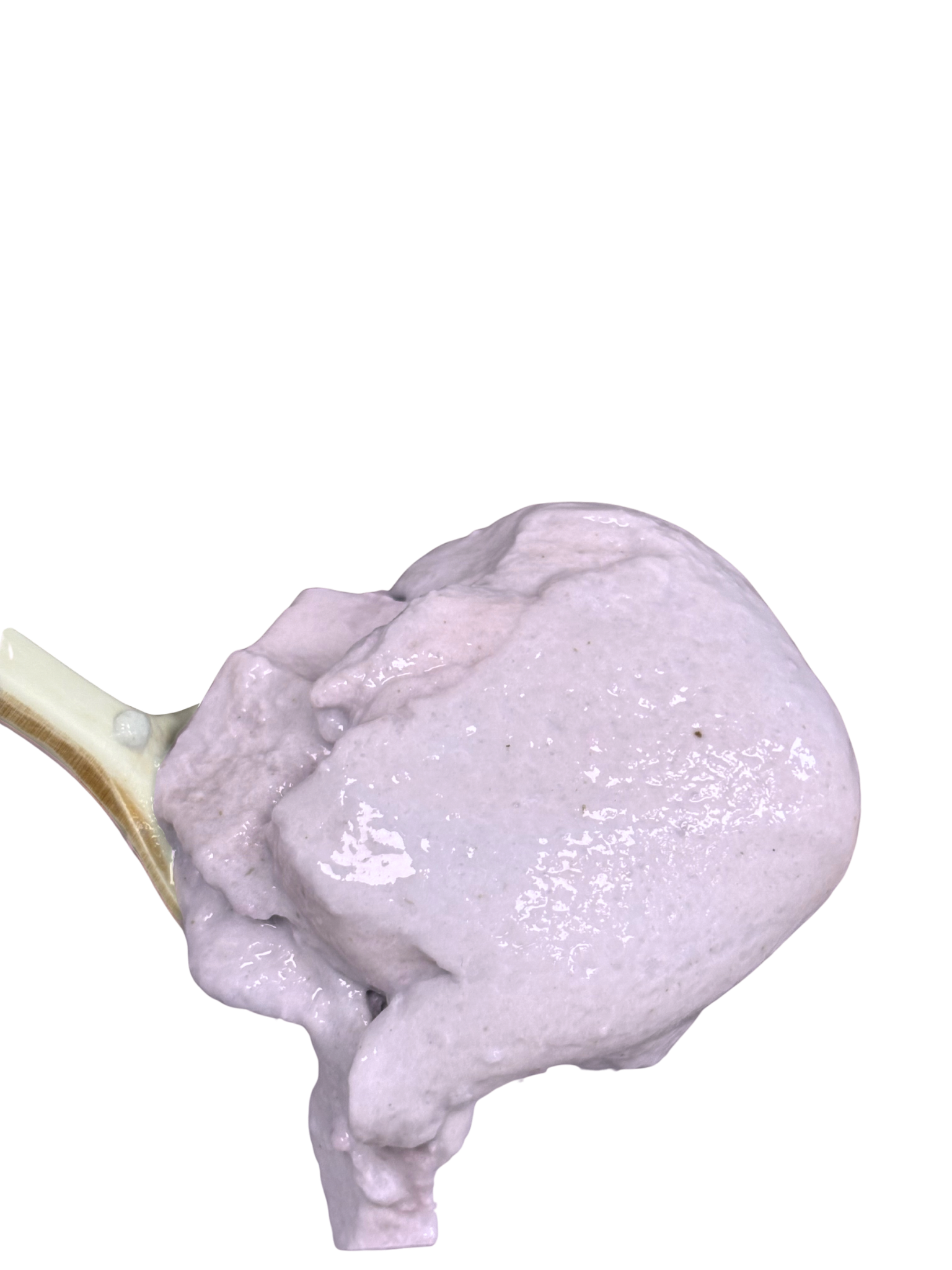 A dollop of pale purple mixture on a beige spoon.