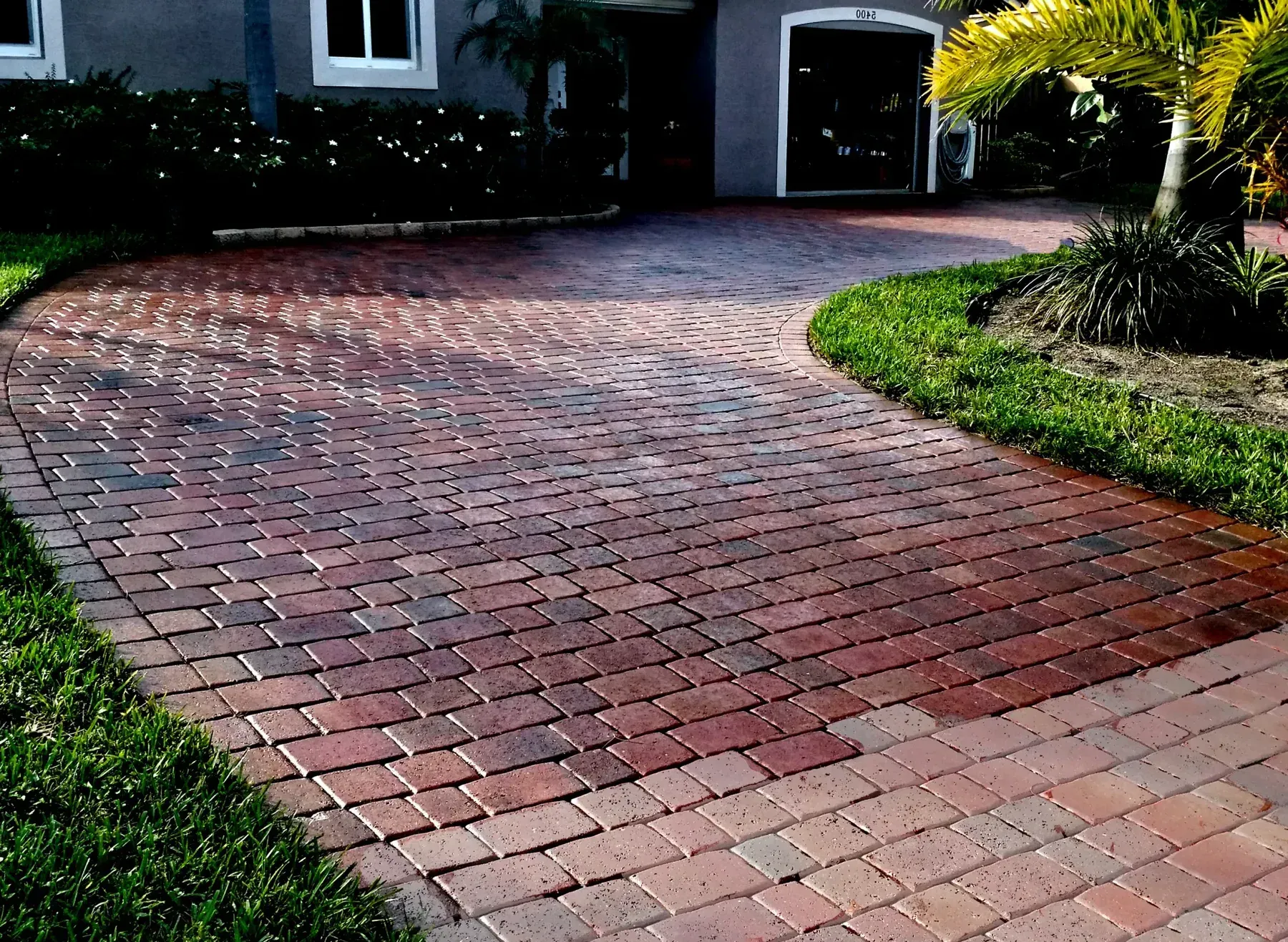 A brick driveway leads to a house with a garage