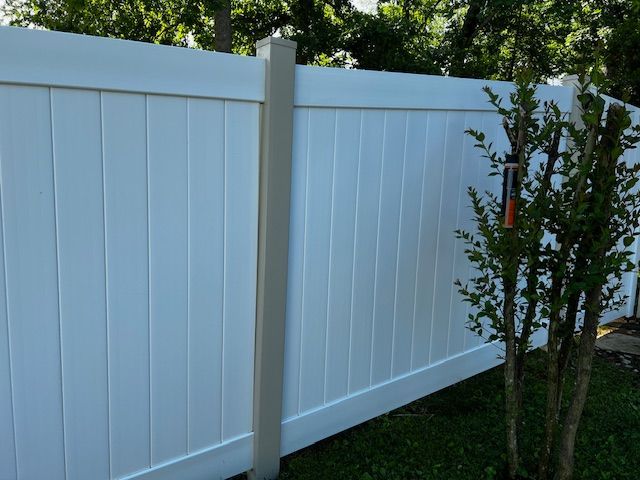A white vinyl fence with a tree in the background.