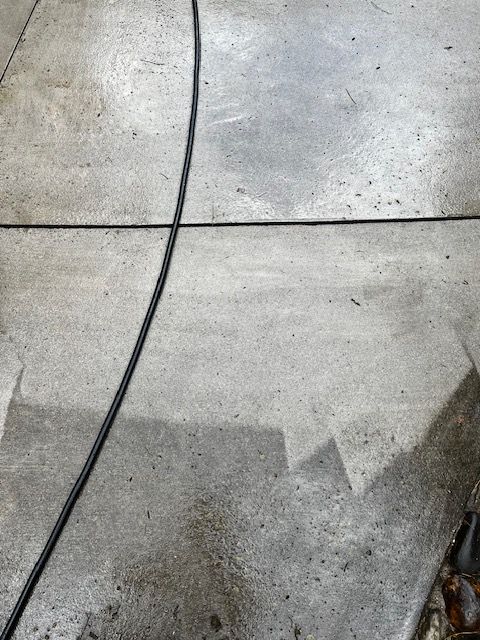 A close up of a concrete floor with a hose attached to it.