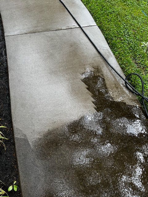 A sidewalk is being cleaned with a hose. Cleaning by 865 Power Wash