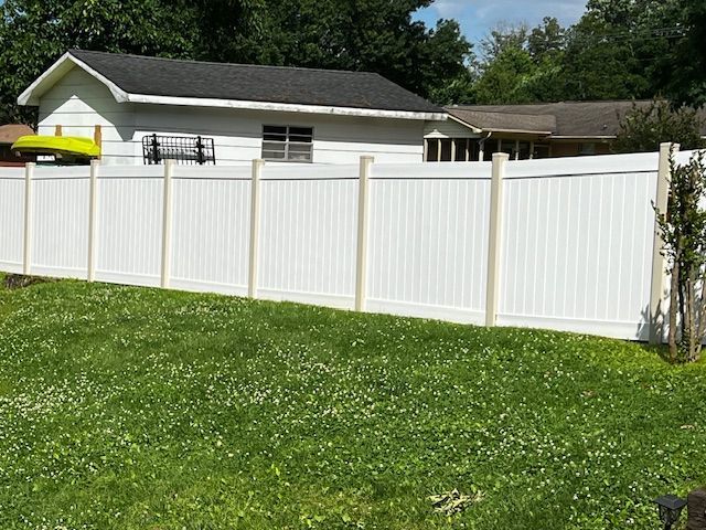 A white fence surrounds a lush green yard in front of a house. Cleaning by 865 Power Wash