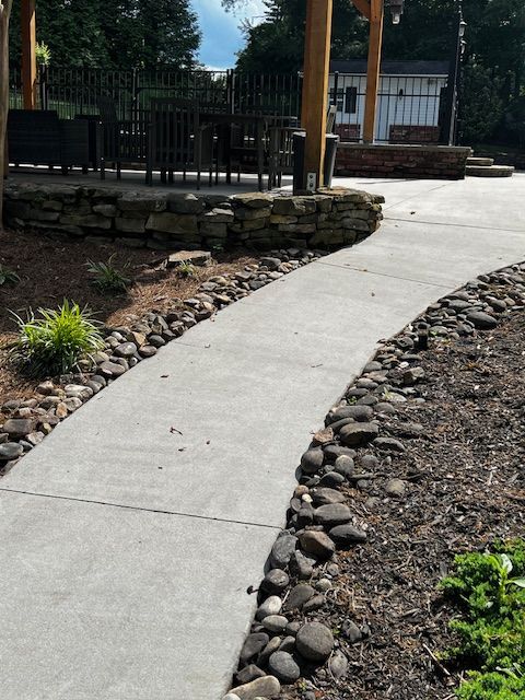 A concrete walkway is surrounded by rocks and plants. v