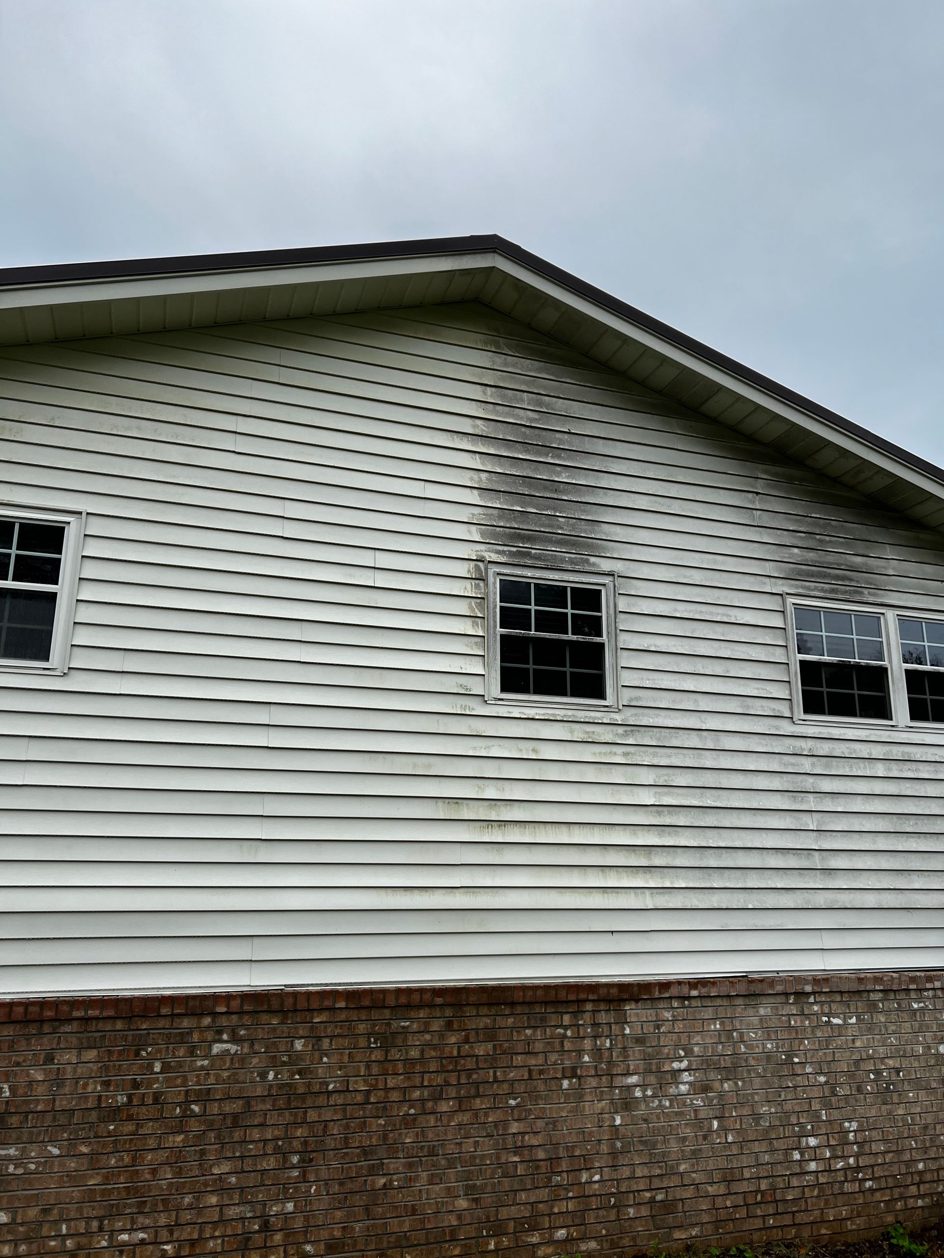 A white house with a lot of windows and a brick wall.