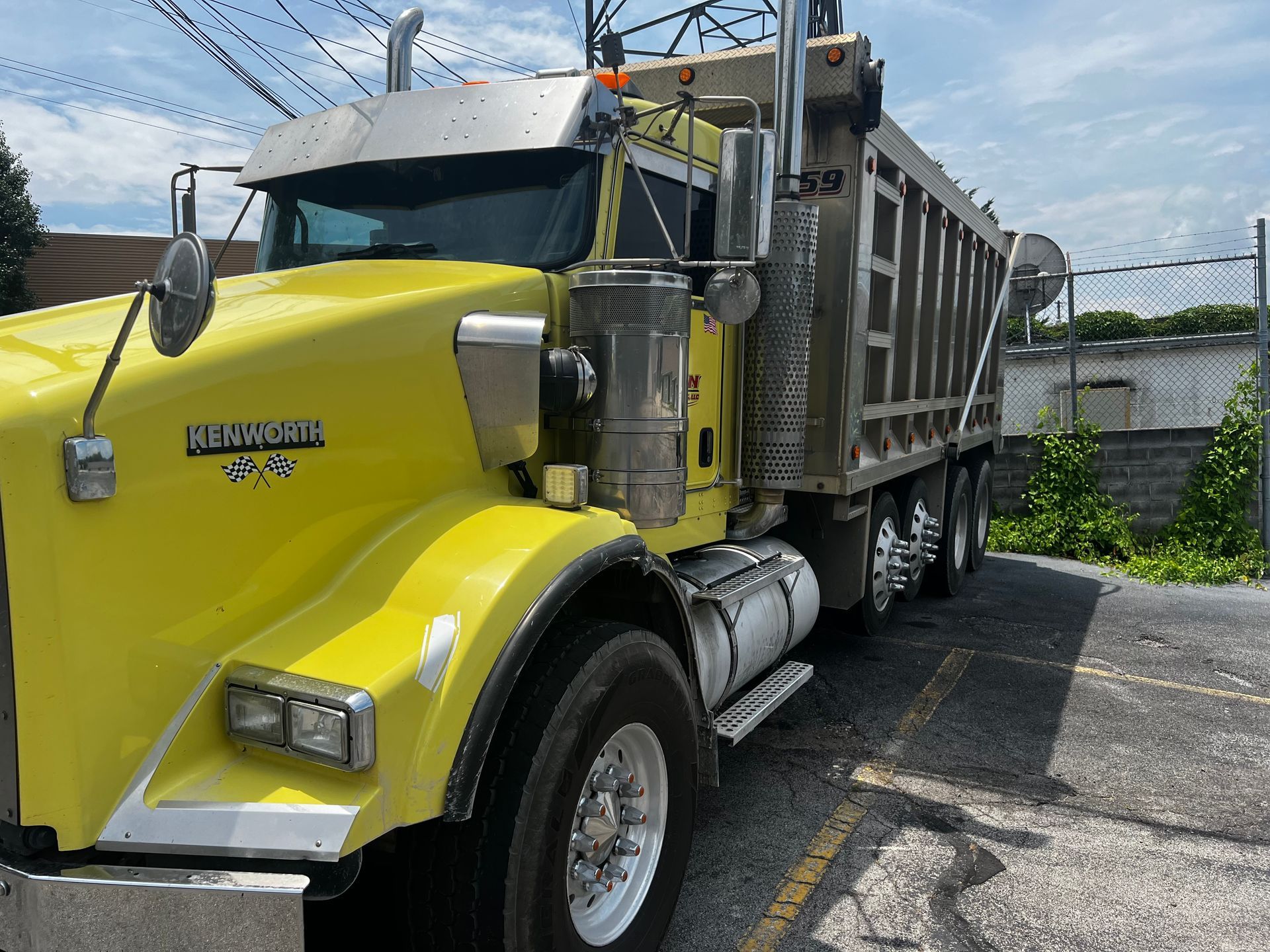 A yellow dump truck is parked on the side of the road