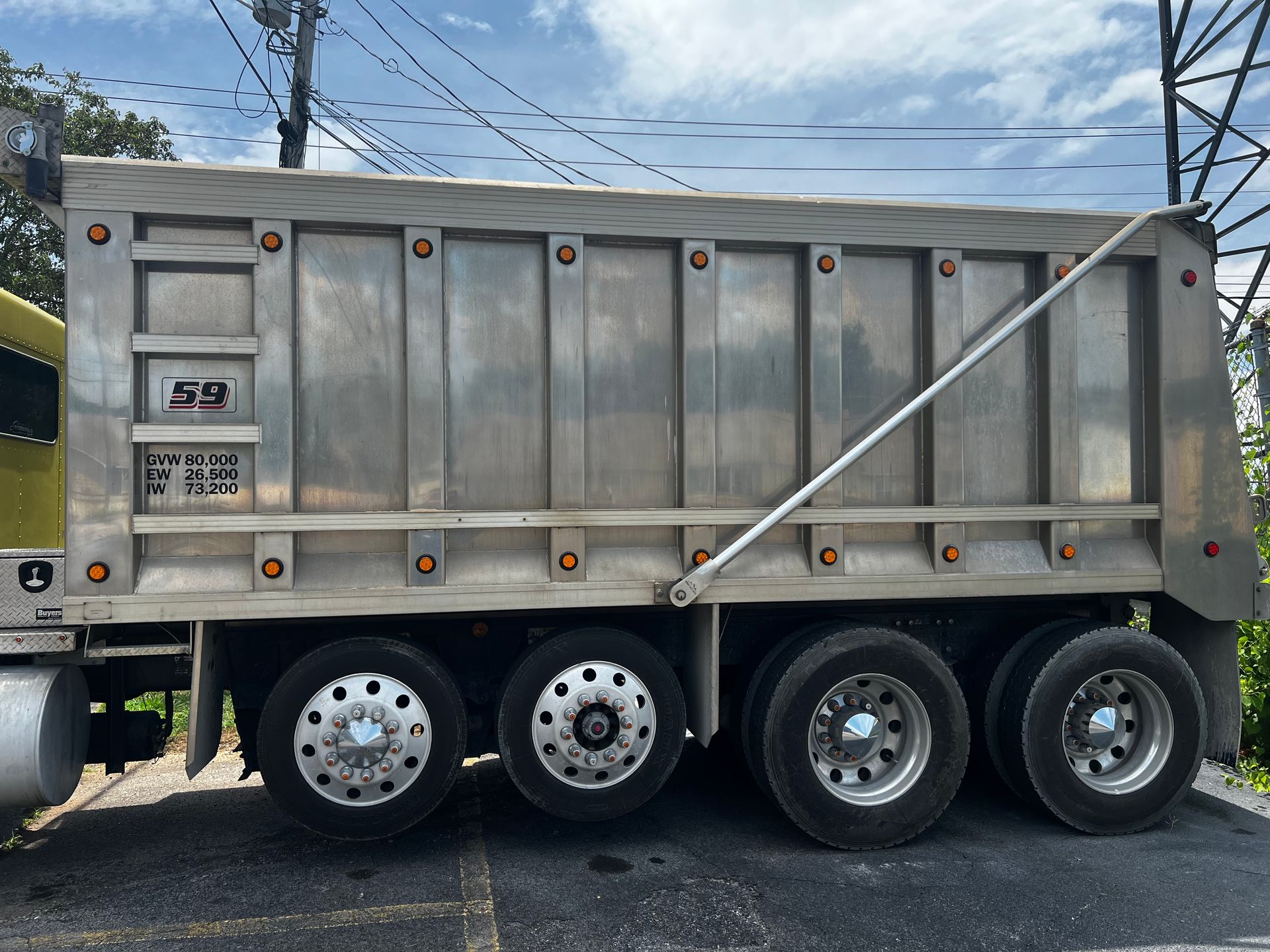 A large aluminum dump truck is parked on the side of the road.