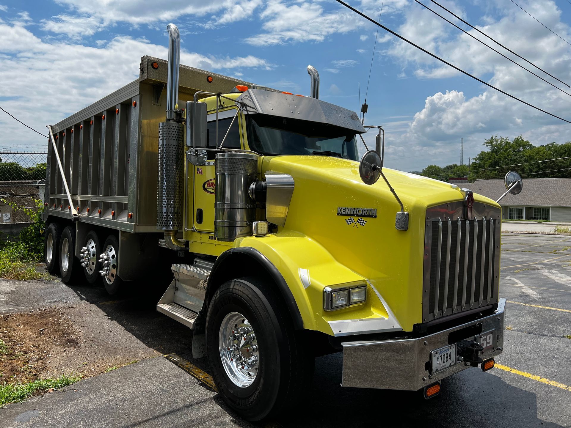 A yellow dump truck is parked on the side of the road.