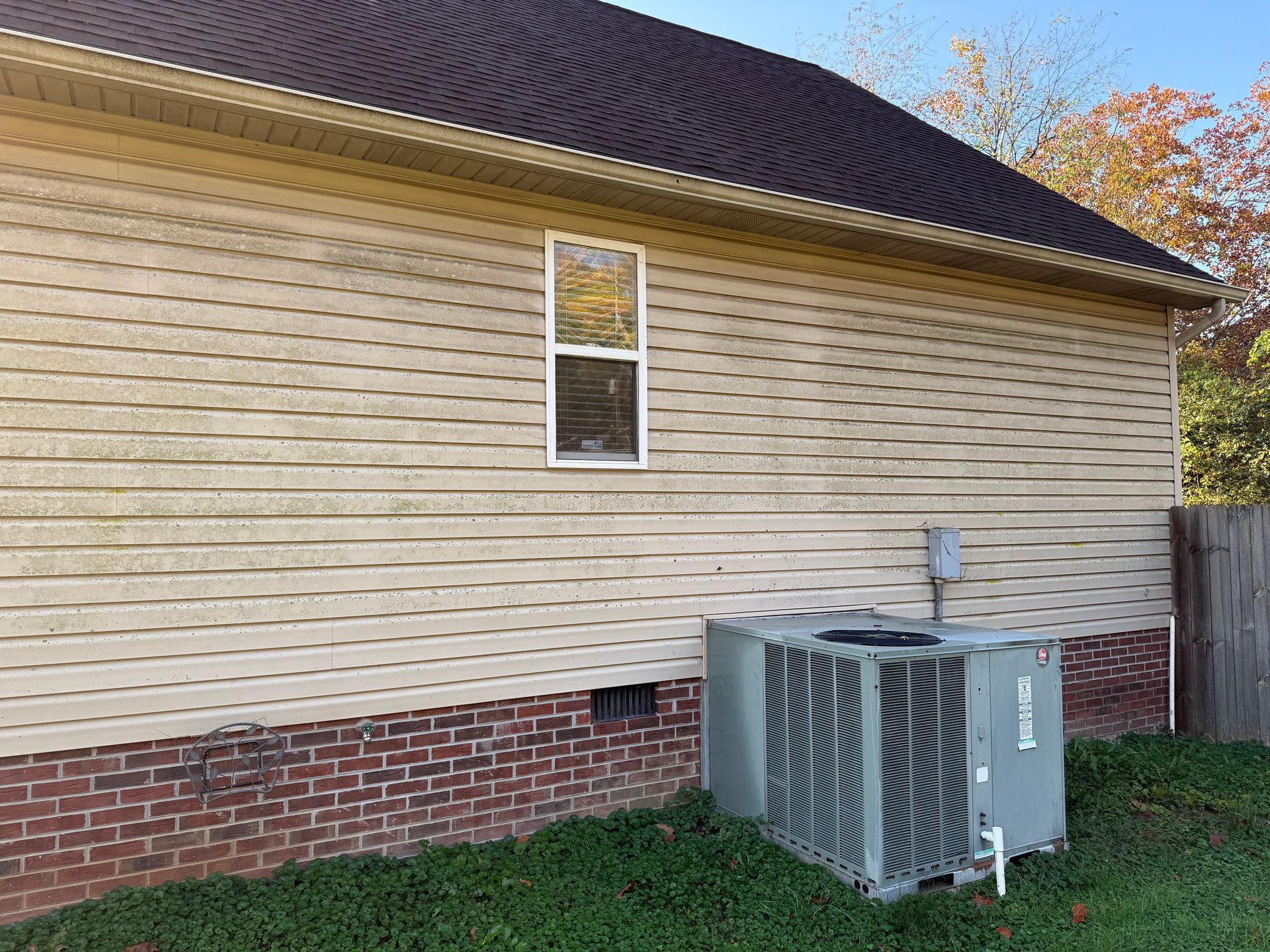 A house with a window and an air conditioner on the side of it.