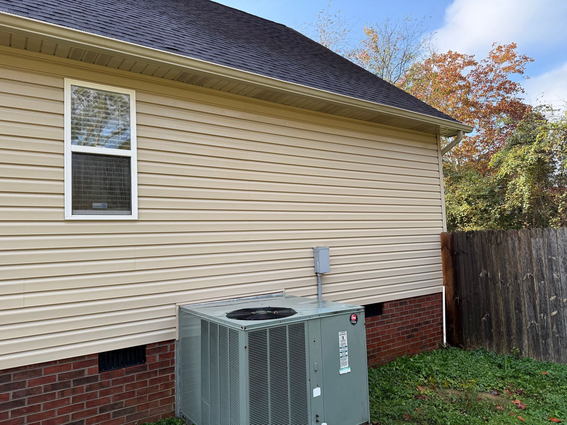 A house with a window and an air conditioner on the side of it.