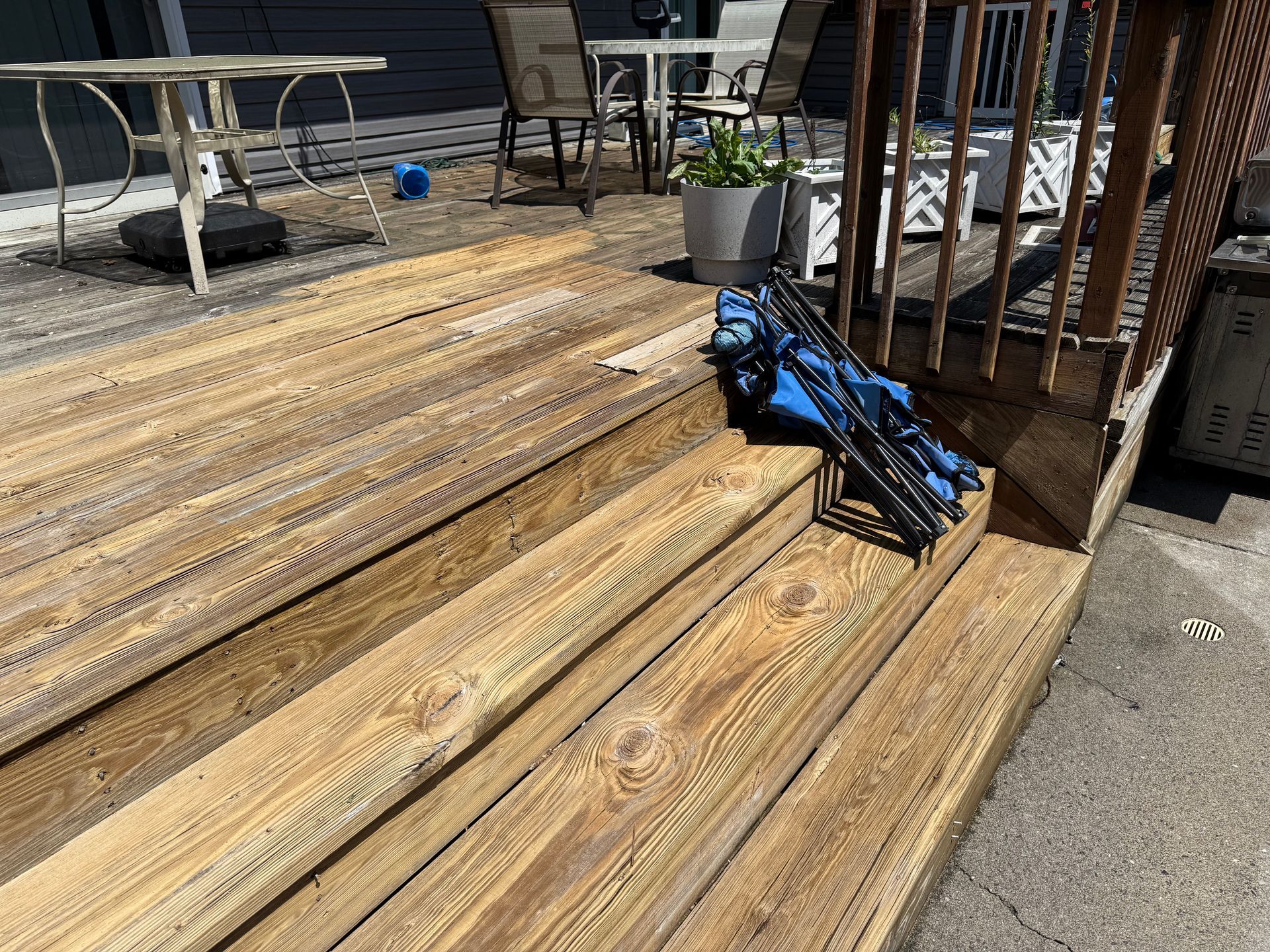 Wooden deck with steps; patio furniture and blue object visible.