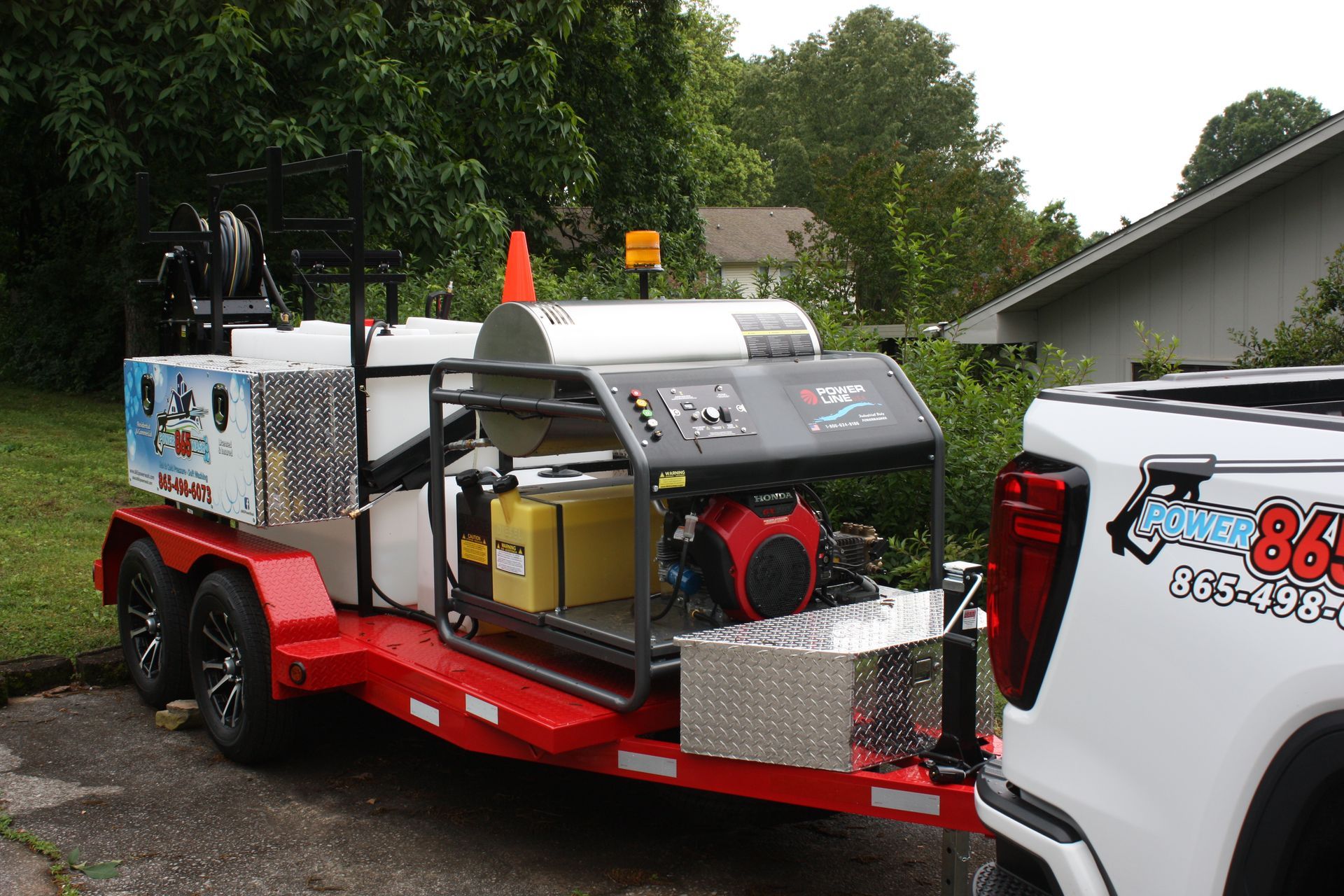 A white truck is parked next to a trailer with a machine on it.