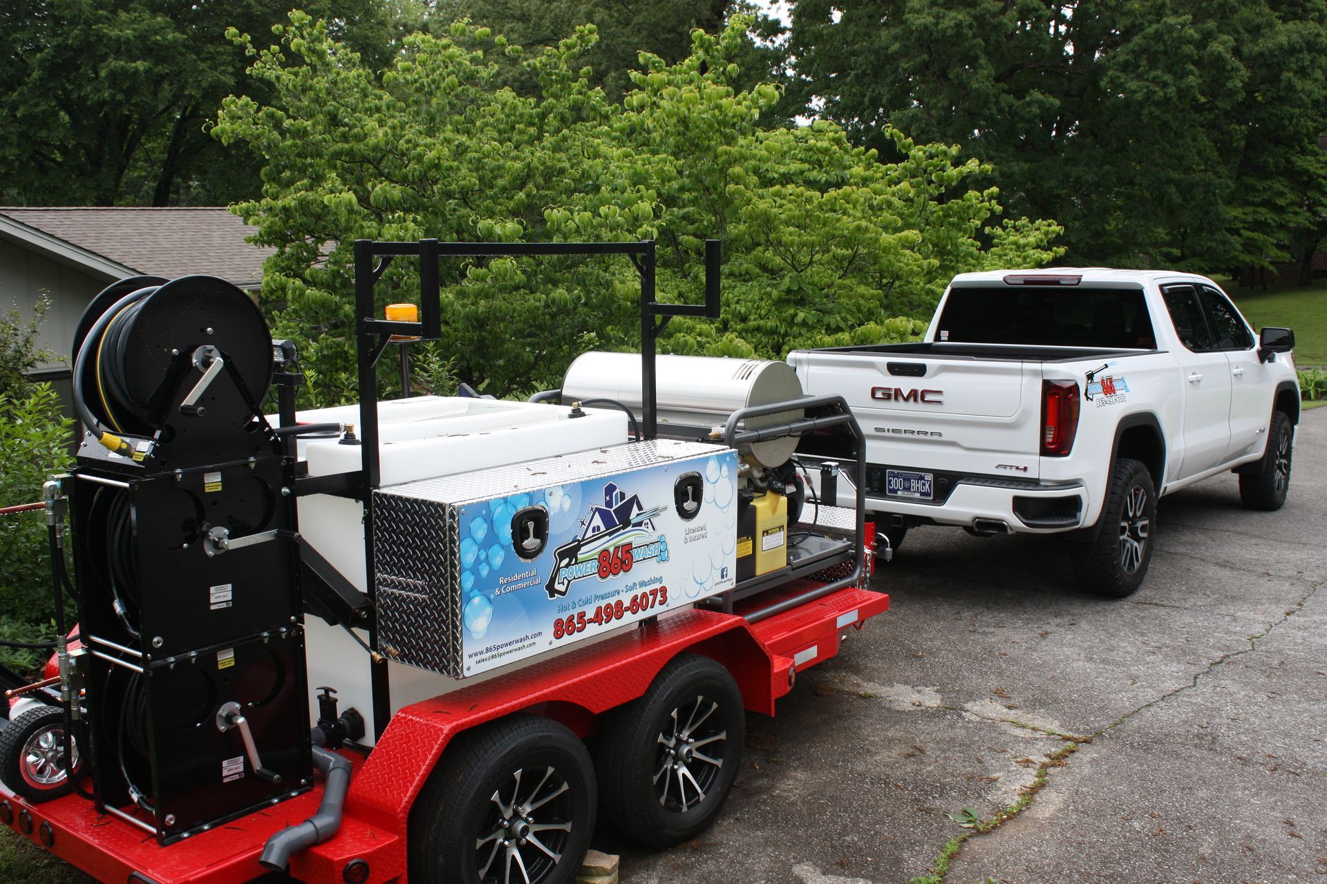 A white truck with a trailer attached to it is parked in a driveway.